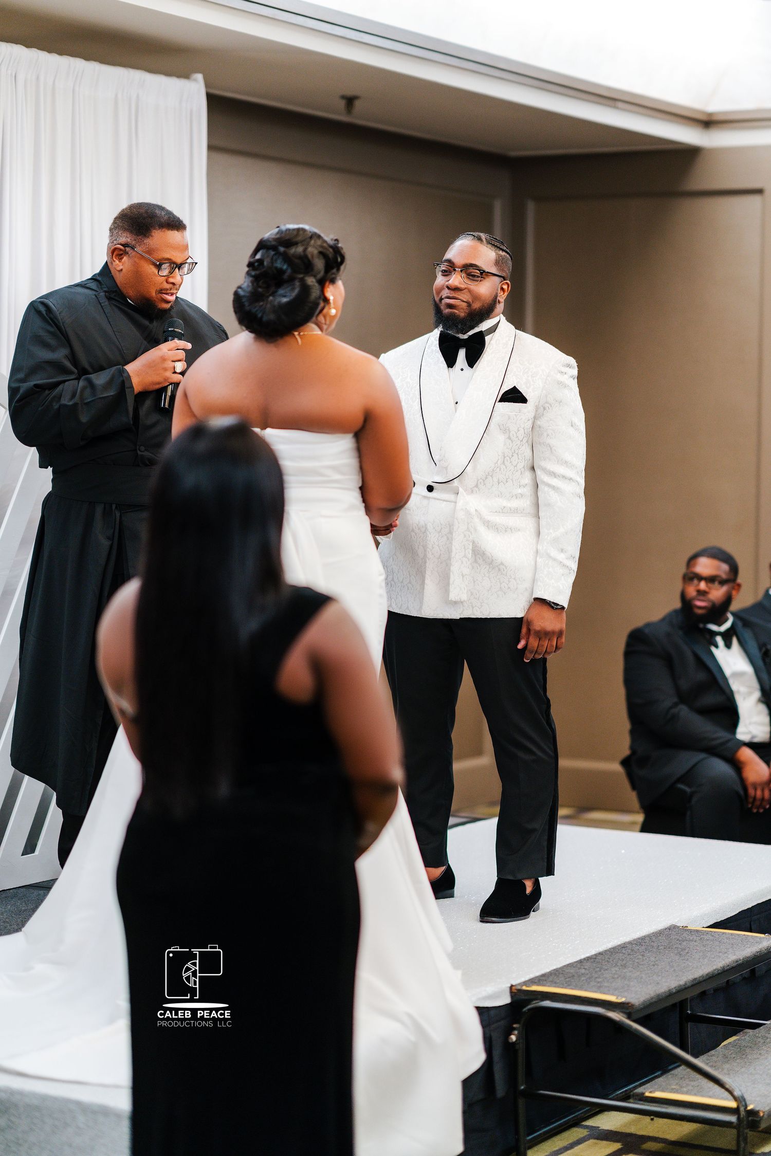 Wedding party members gather in formal black and white attire during pre-ceremony preparations.