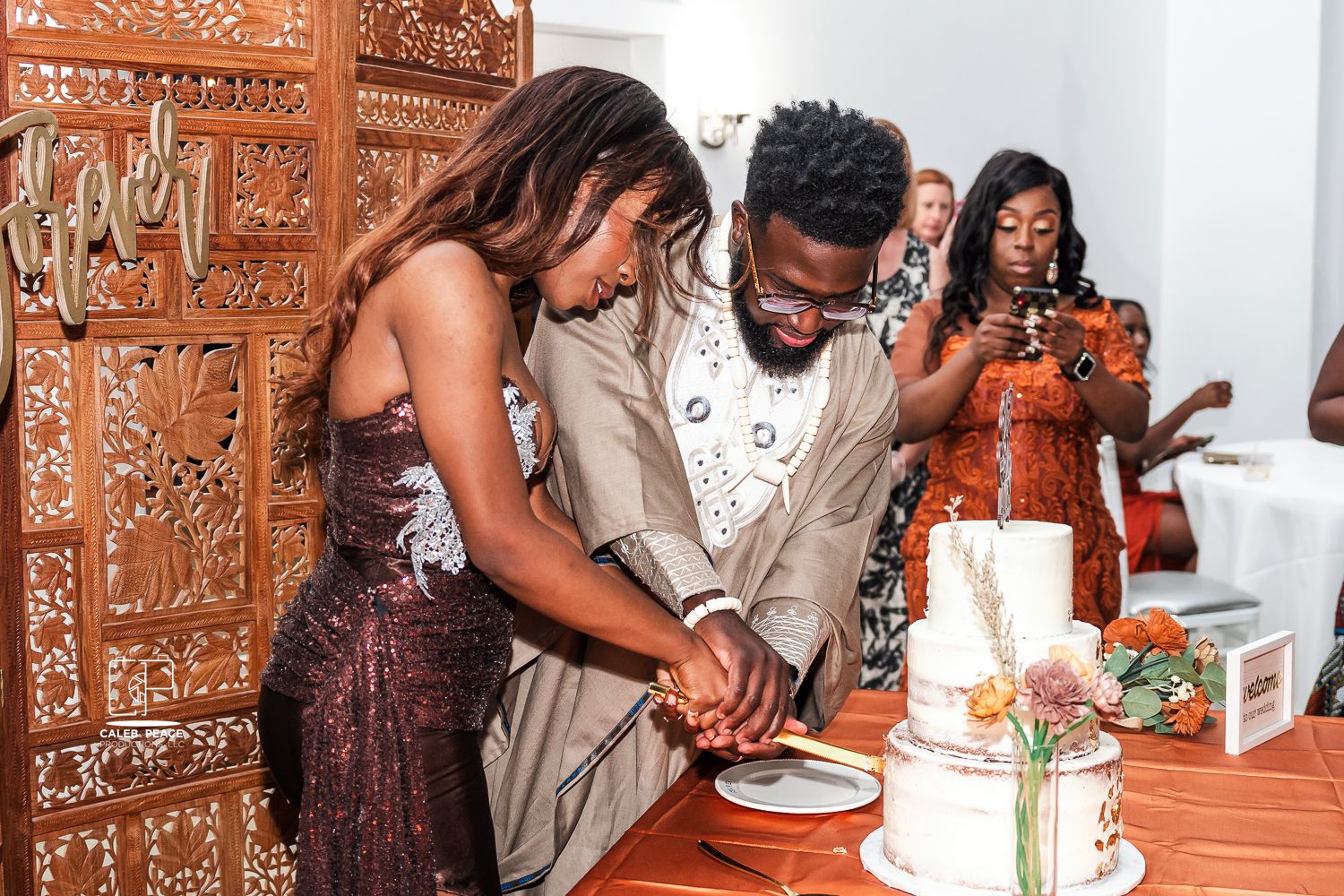 Wedding couple cuts their elegant white tiered cake together during reception celebration.
