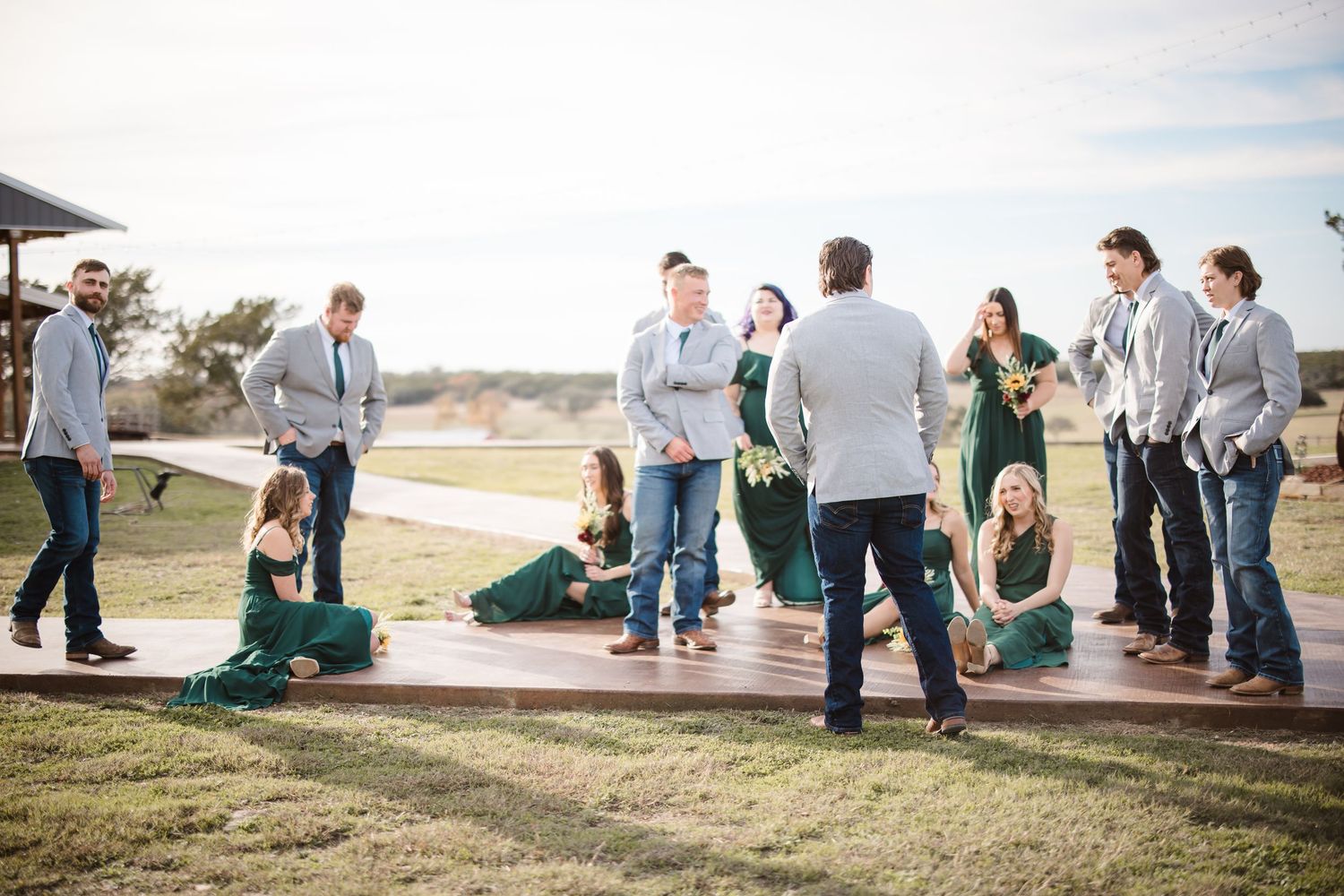 Wedding guests and party members gather on a grassy hillside for outdoor group photos.