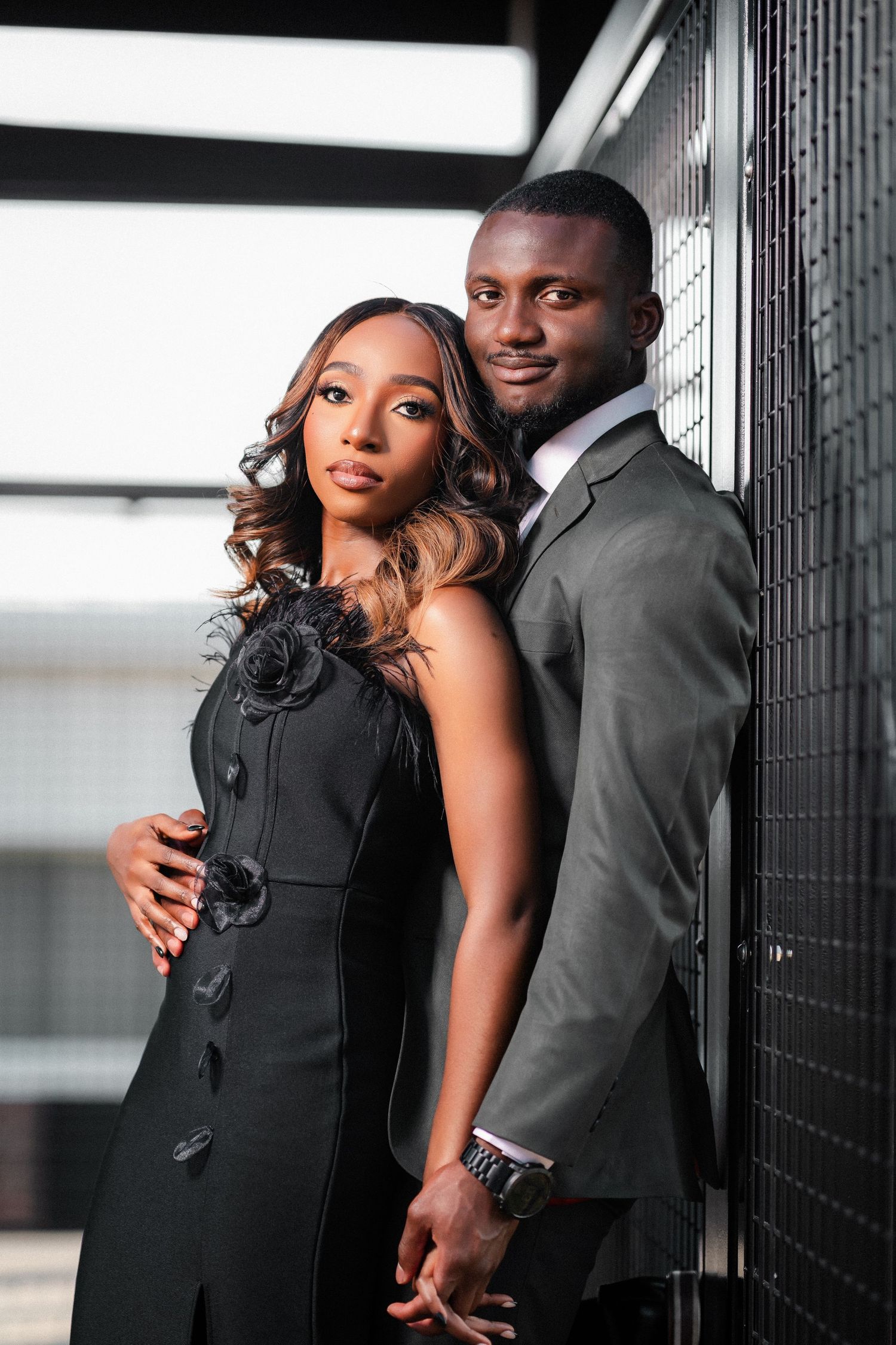 Elegant couple in black and grey formal wear posing against dark background.