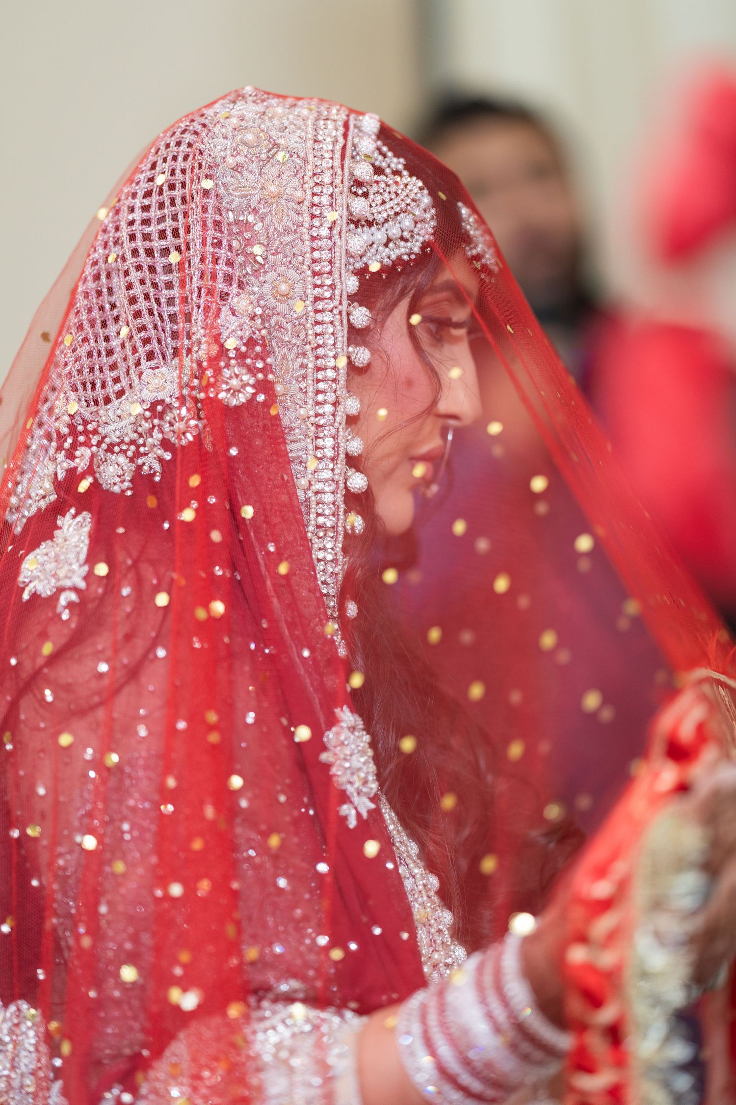 Close-up of red and silver beaded bridal veil with intricate embroidery details.
