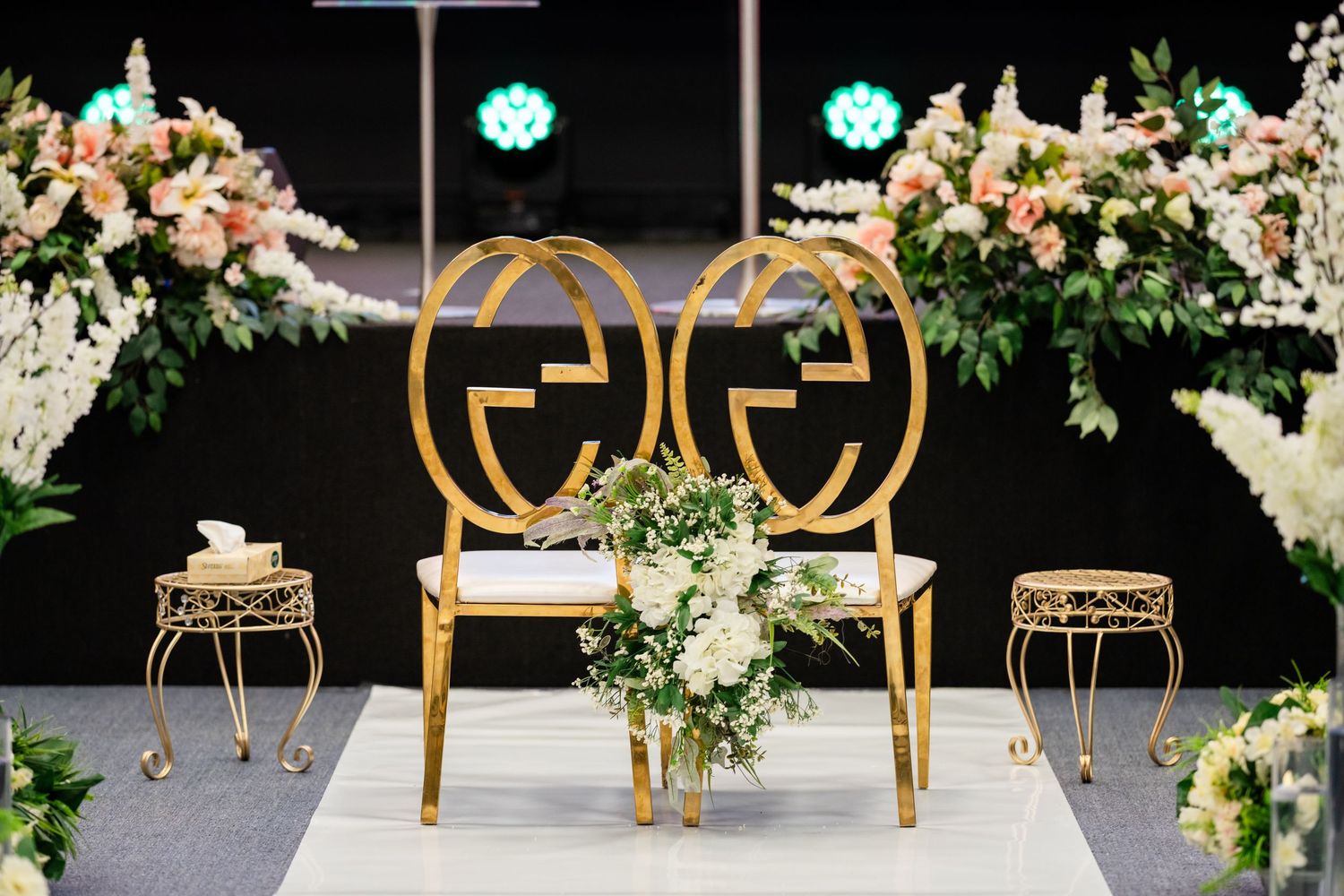Wedding ceremony setup with gold chairs and floral arrangements.
