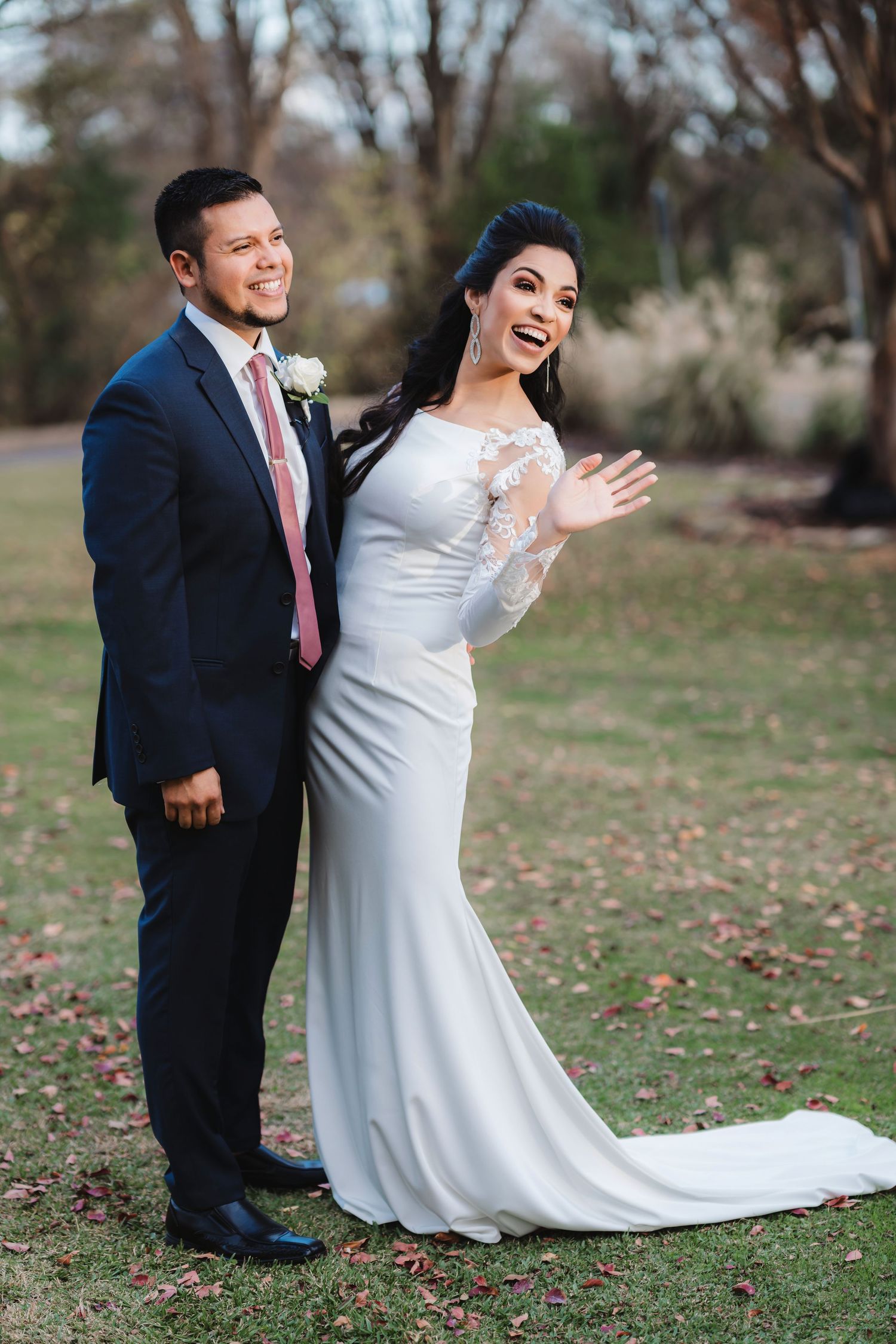 A couple in wedding attire share a joyful moment outdoors on their special day.