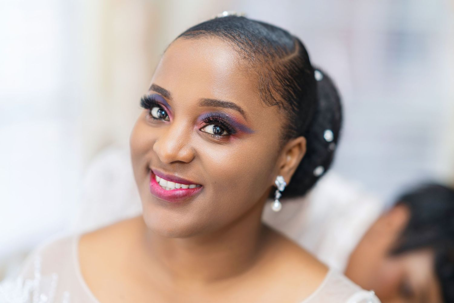 Beautiful bridal portrait showing radiant smile, pearl earrings and elegant makeup on wedding day.