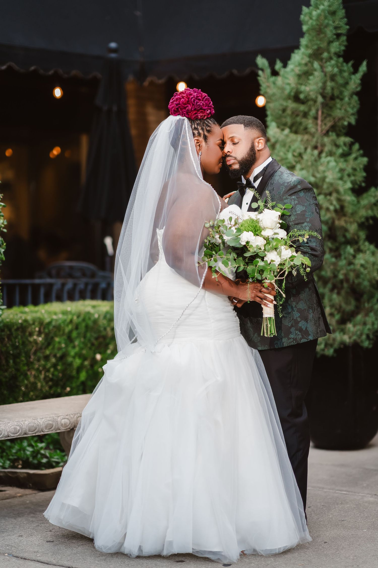 Romantic wedding portraits with white bridal gown and bouquet against outdoor greenery.