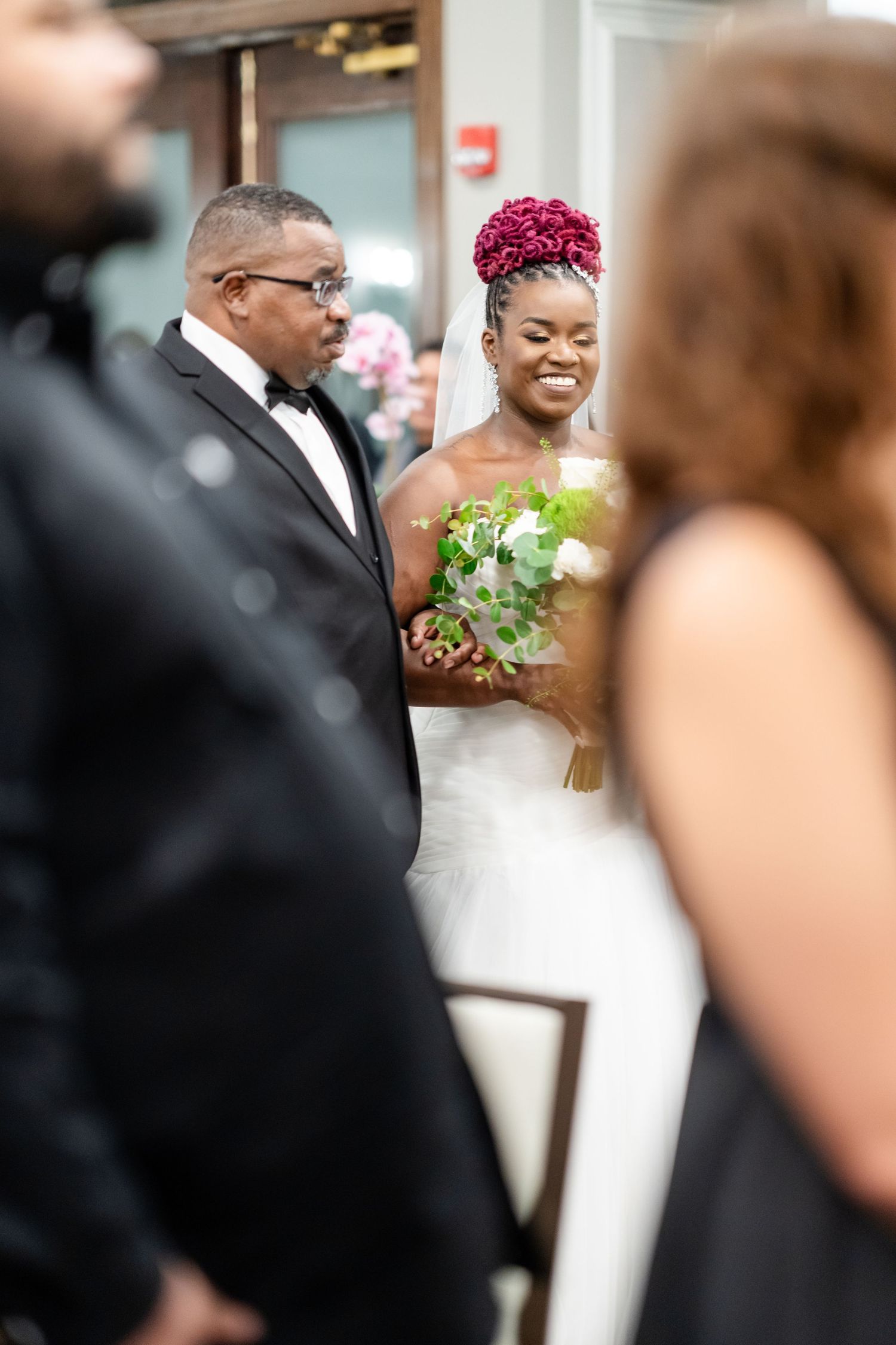Wedding ceremony candid shots with guests in formal attire and white floral decorations.