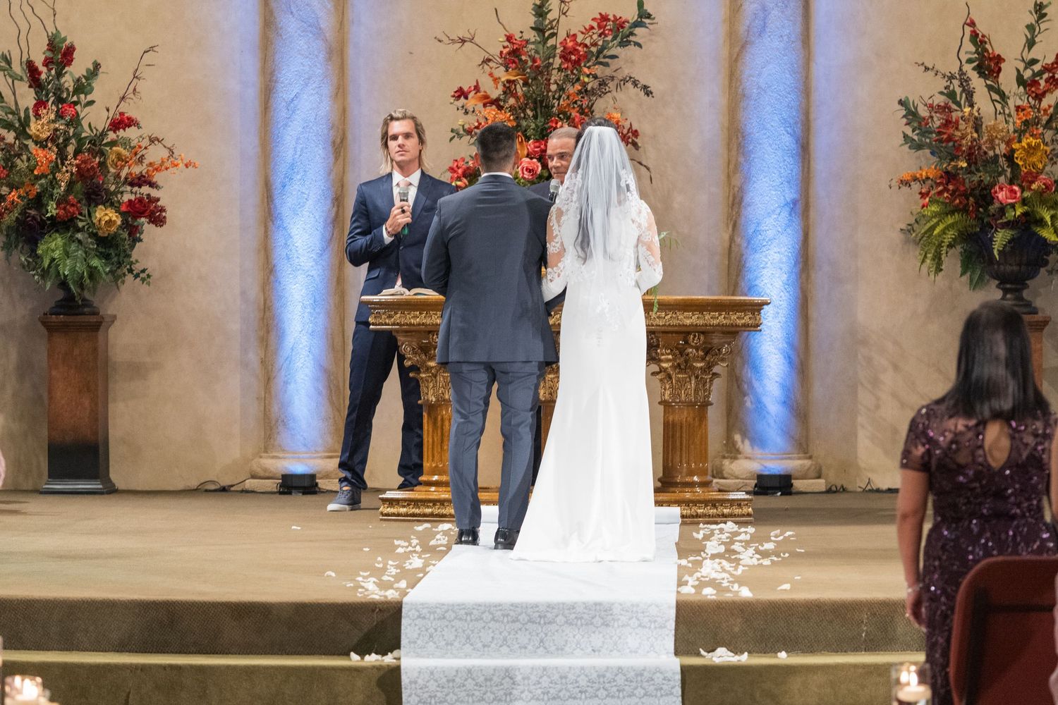 Wedding ceremony setup with floral arrangements and guests seated in a traditional church setting.