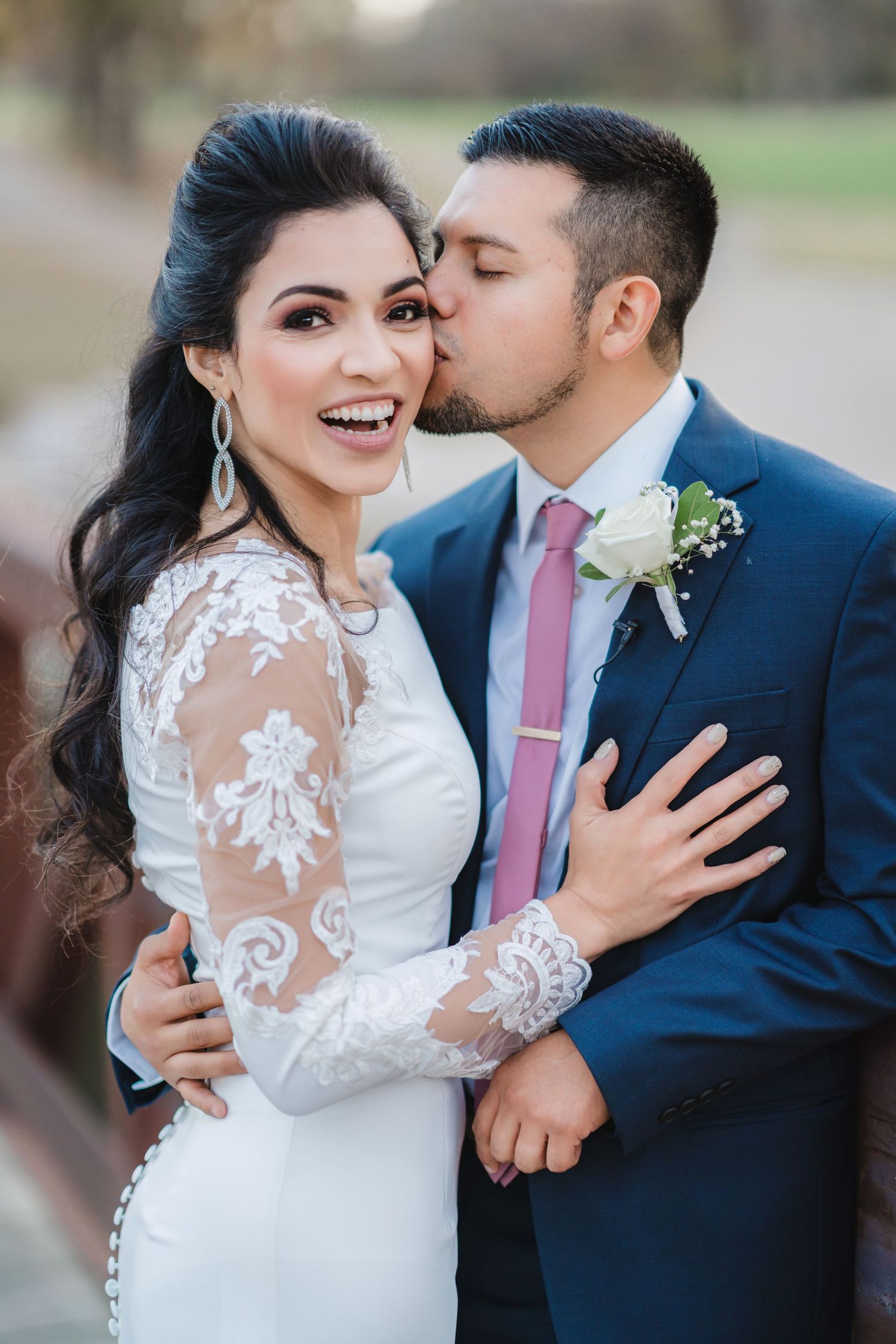 A romantic wedding moment captured with the couple embracing in white dress and navy suit.