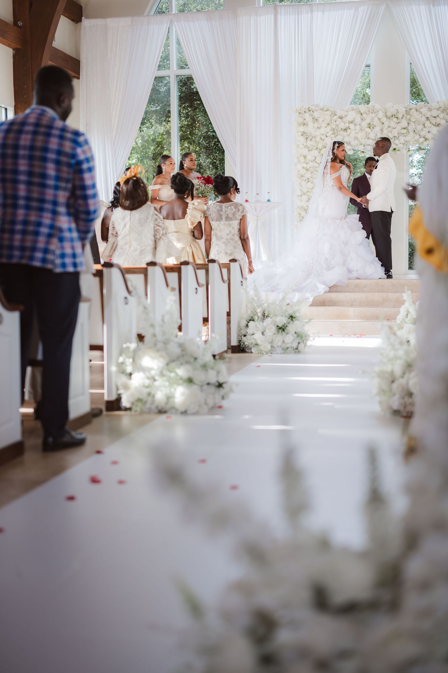 White draped ceremony space with floral decorations and chairs set up for a wedding.