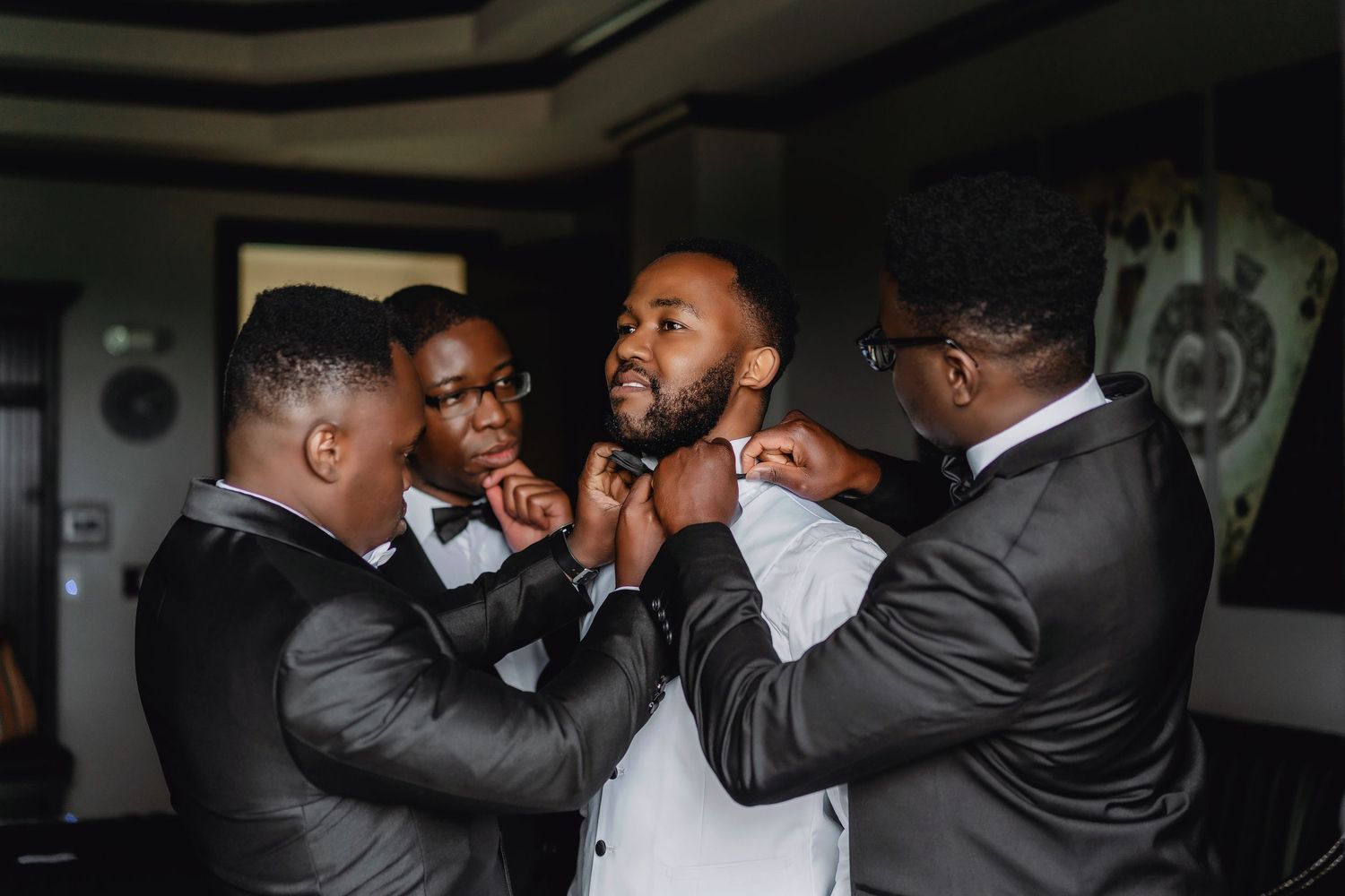A group of formally dressed people embrace in celebration during an indoor event.