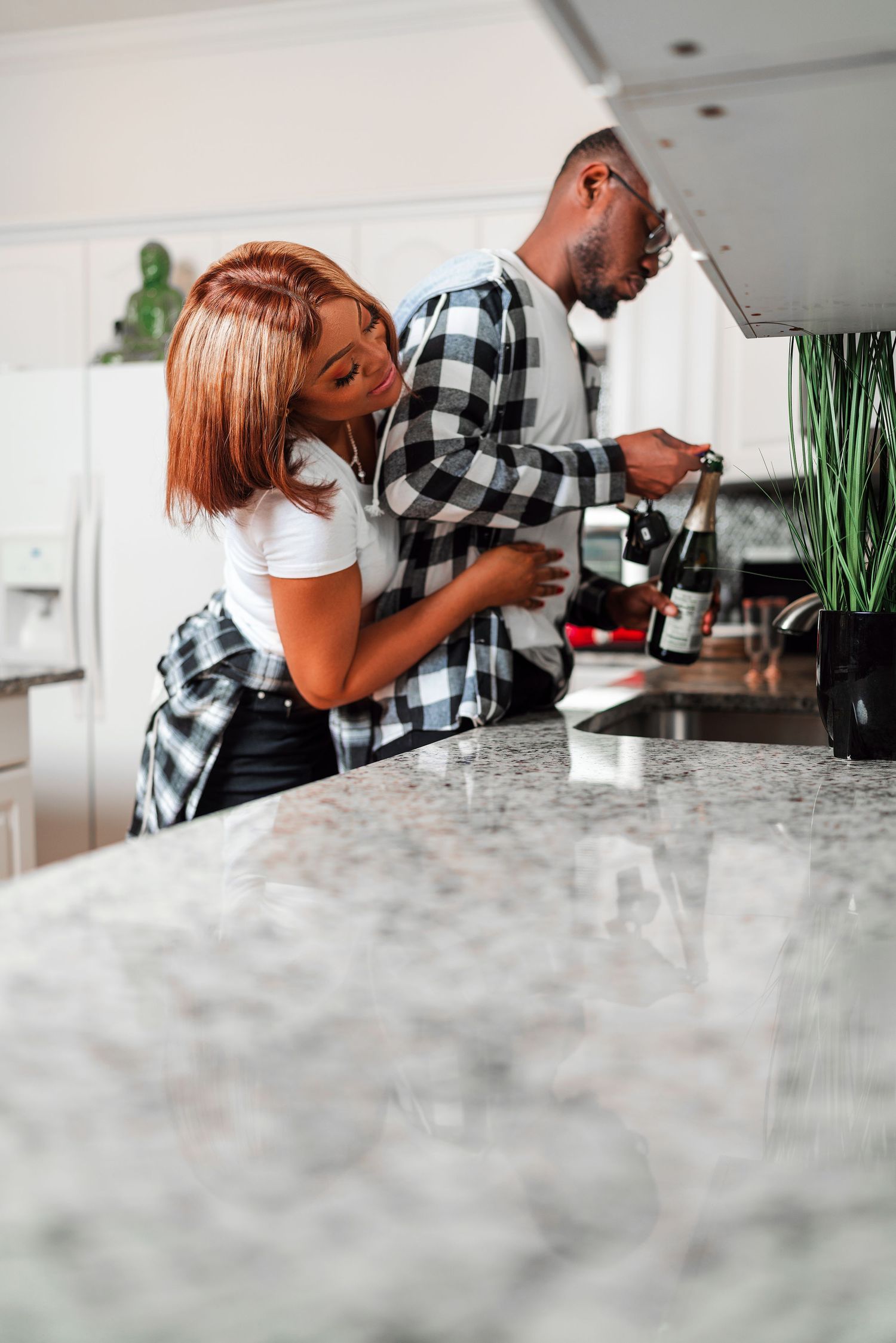 Two people enjoying wine together at a marble kitchen counter in a modern home setting.