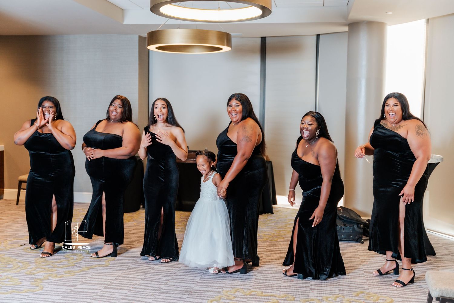 Wedding party members in black attire pose casually on the floor for creative group photos.