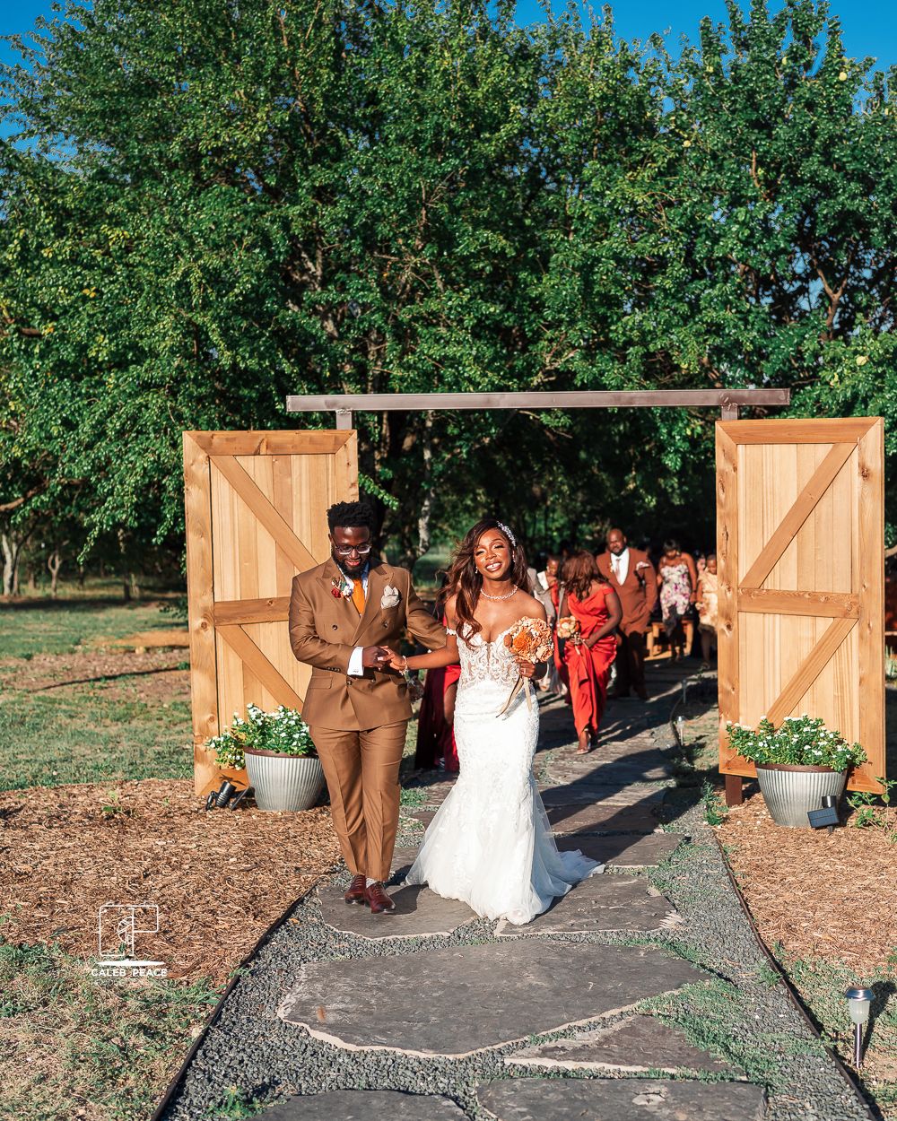 Outdoor wedding venue with wooden barn doors and decorative barrels creating a rustic entrance.