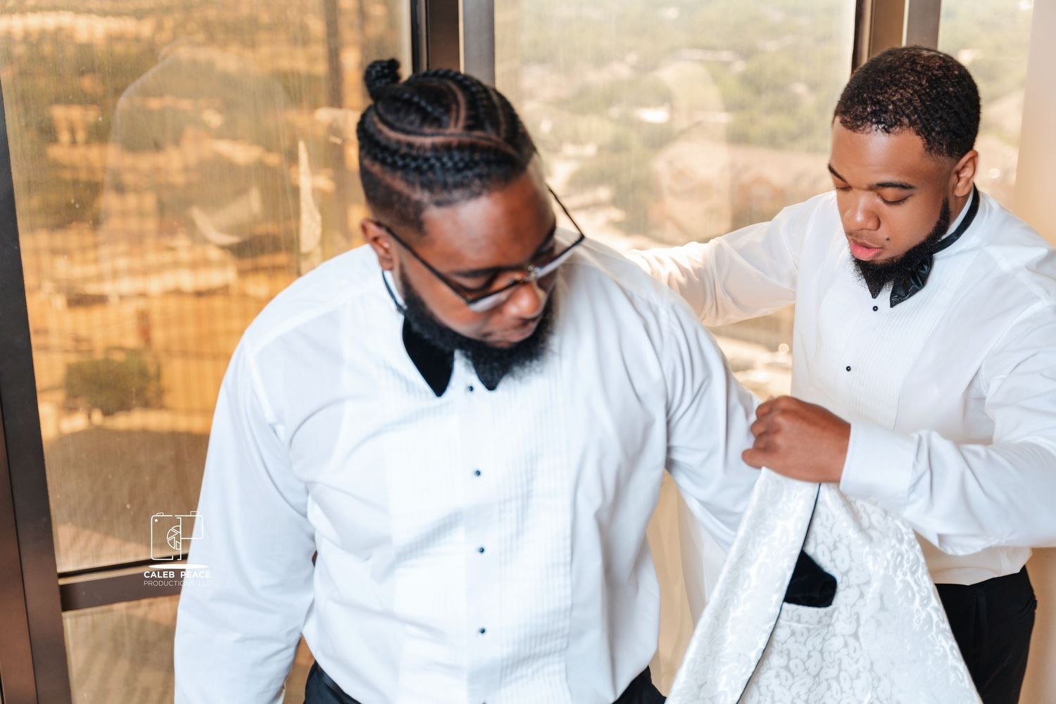Groomsmen in white tuxedos and black bowties preparing for wedding ceremony.