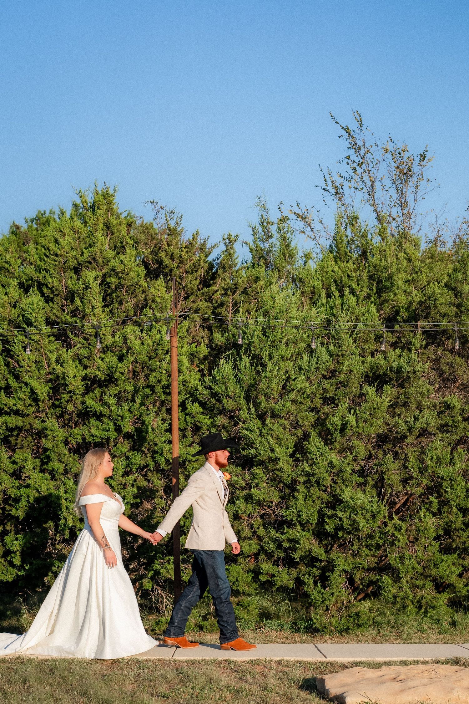 A couple walking together outdoors, with the bride in a flowing white dress.