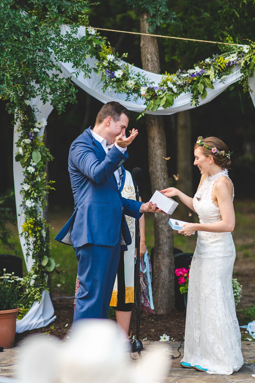 Couple sharing a romantic moment during their outdoor wedding ceremony under trees.