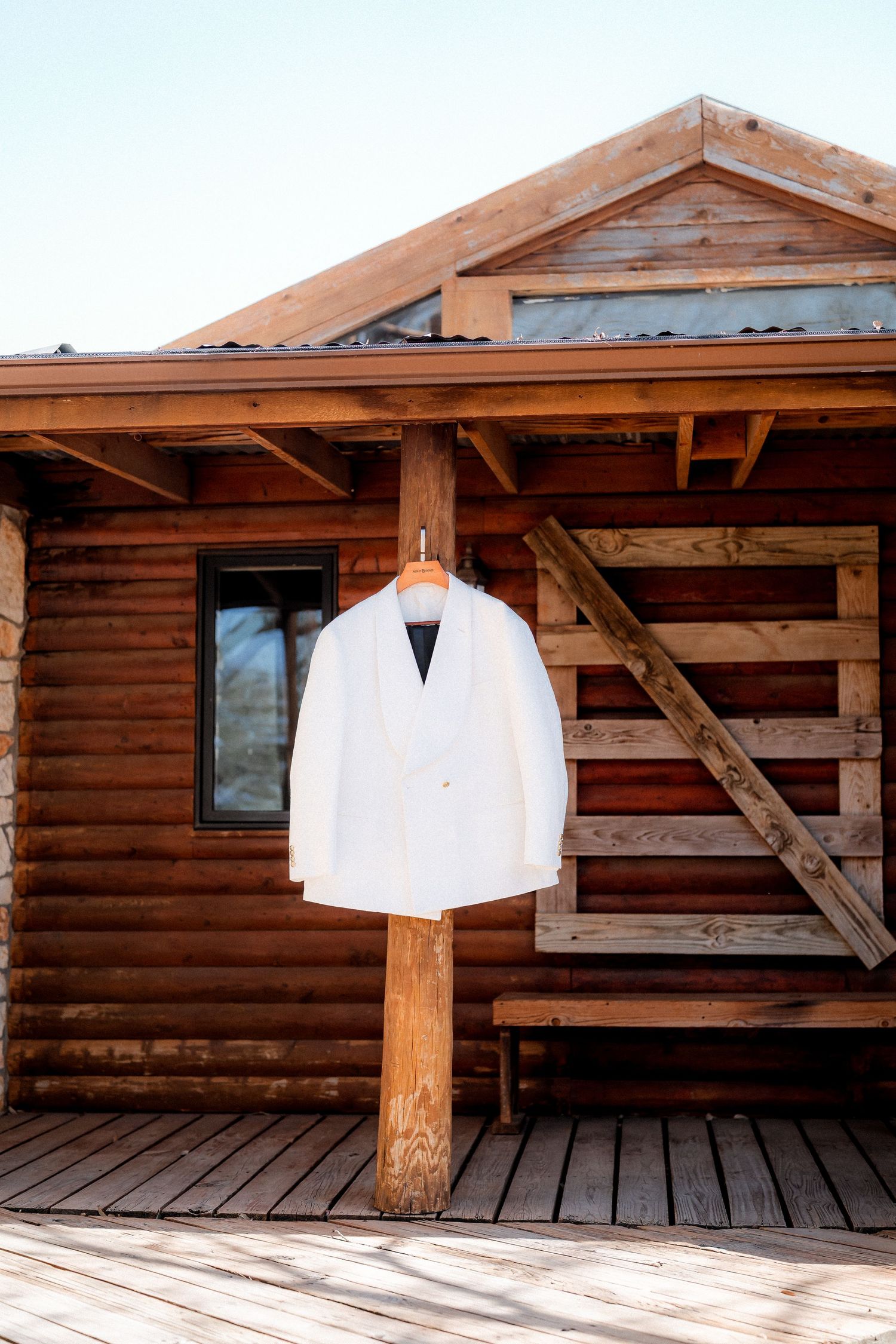 White wedding attire hanging on rustic wooden cabin wall exterior.