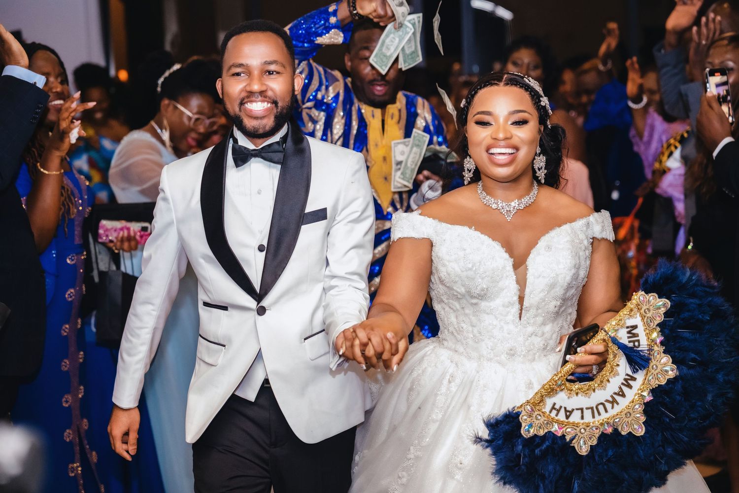 A joyful wedding celebration with guests in royal blue attire dancing at the reception.