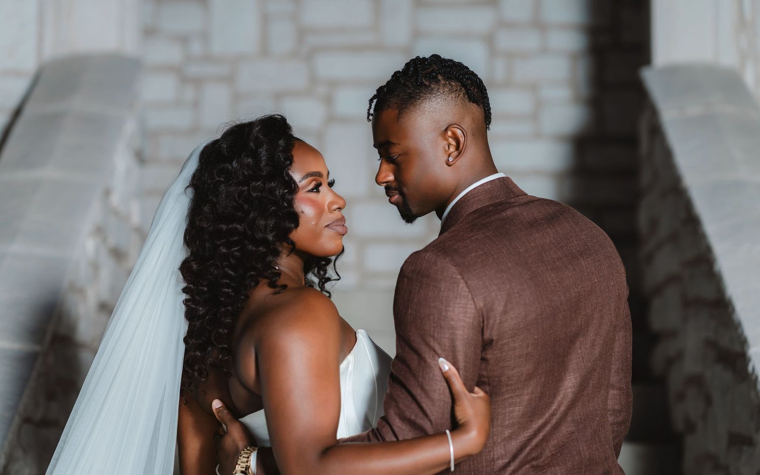 A couple shares intimate moments in a series of romantic wedding photos against a stone wall backdrop.