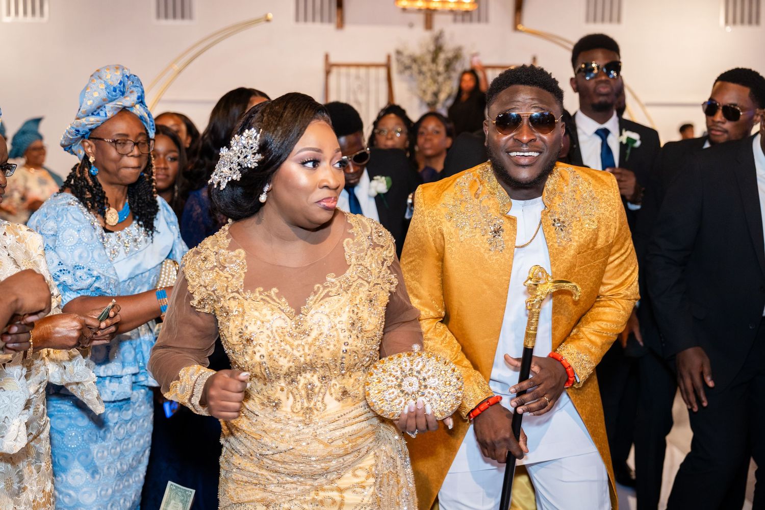 Wedding reception celebration with guests in gold and blue traditional formal attire.