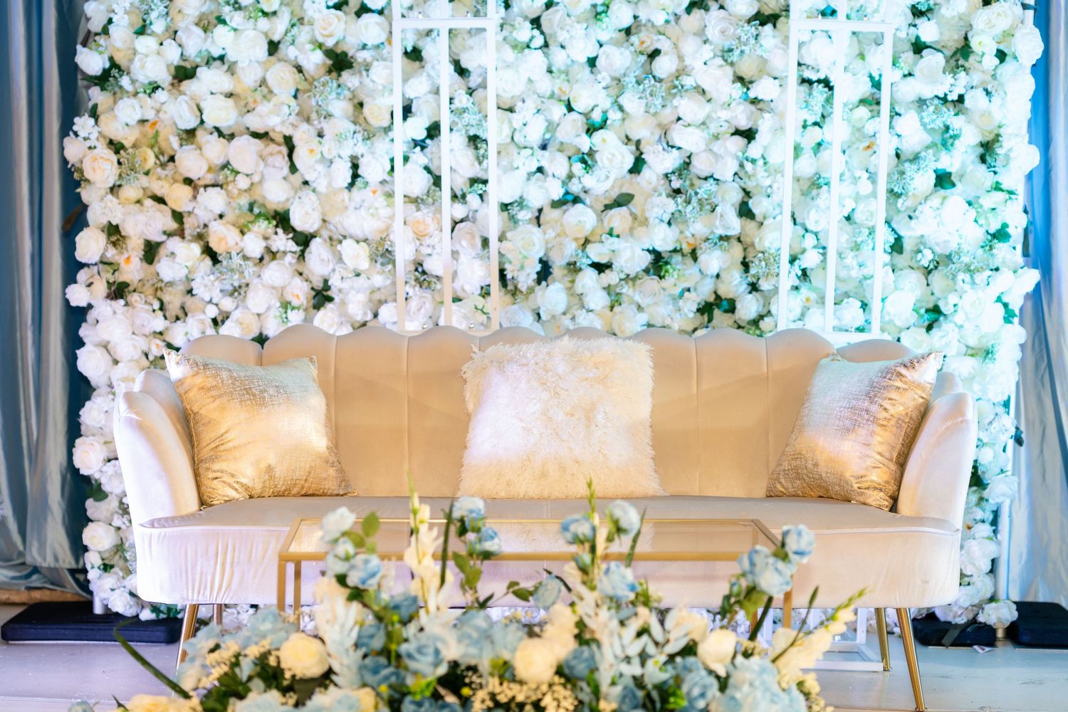 Luxurious white floral wall backdrop with elegant seating arrangement for a formal event.