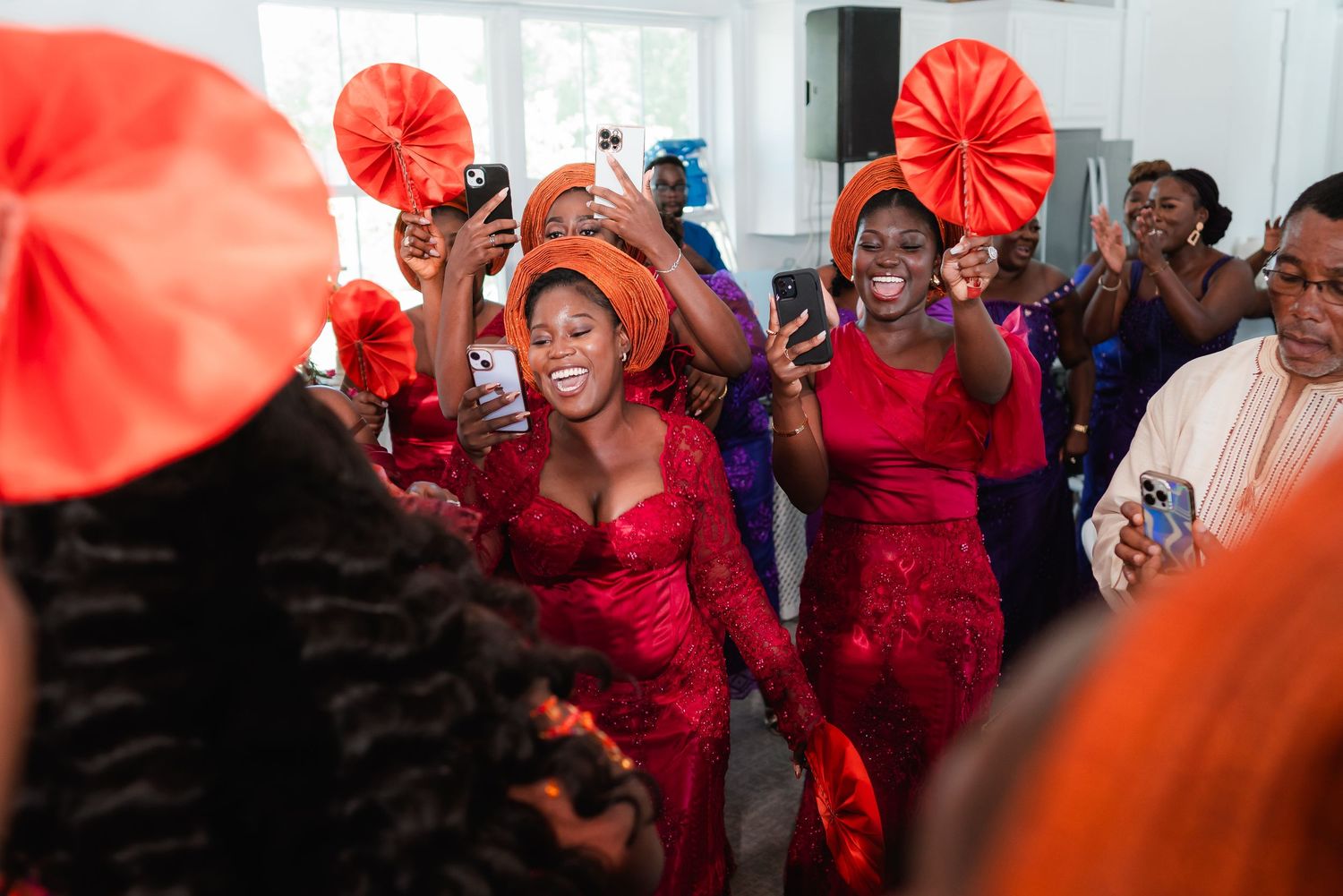 Wedding celebration indoors with decorative red paper fans and festive atmosphere.