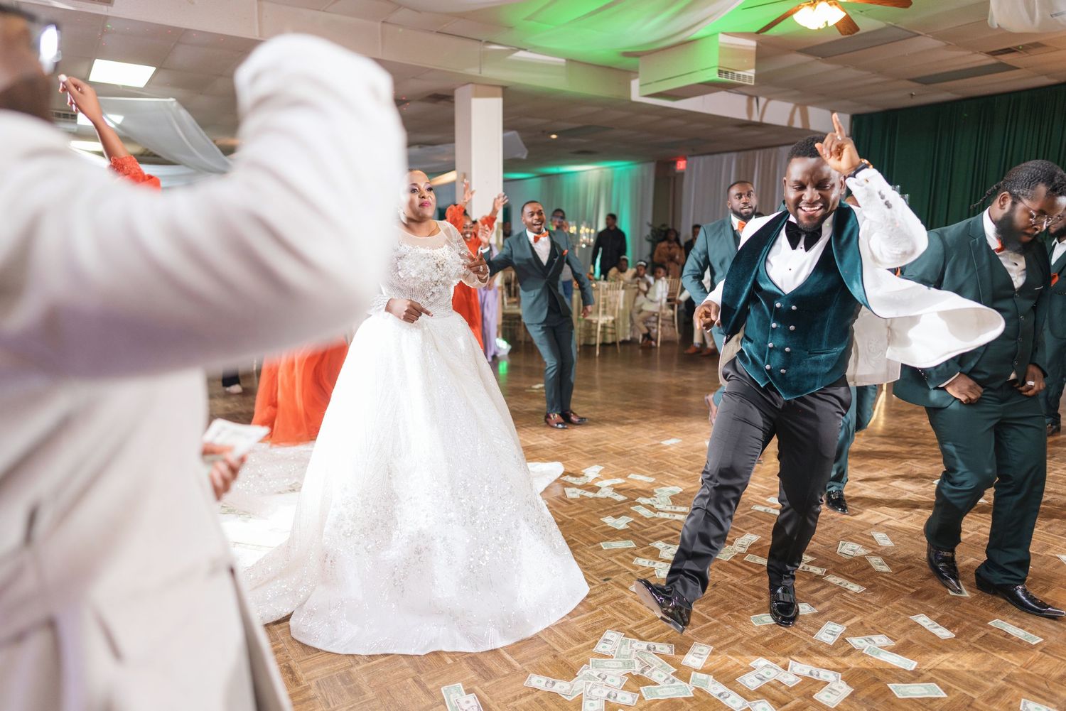 Energetic wedding reception dance party with guests celebrating on confetti-covered floor.