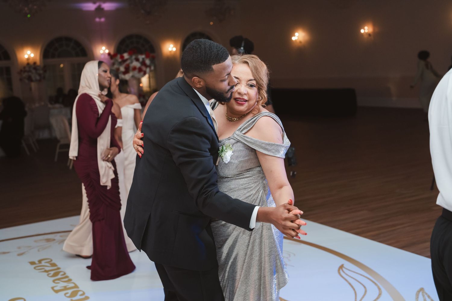 Wedding reception dance floor with couples dancing under ambient lighting.