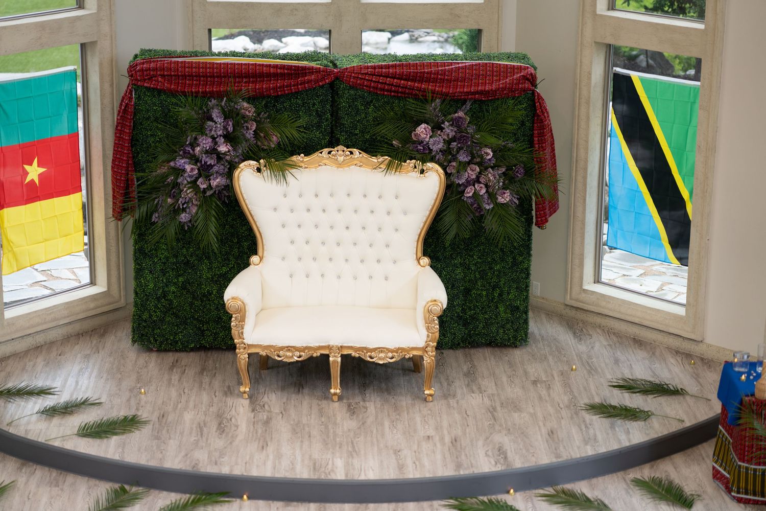Elegant white armchairs and decorative elements arranged in a bright room with green wall accents and window views.