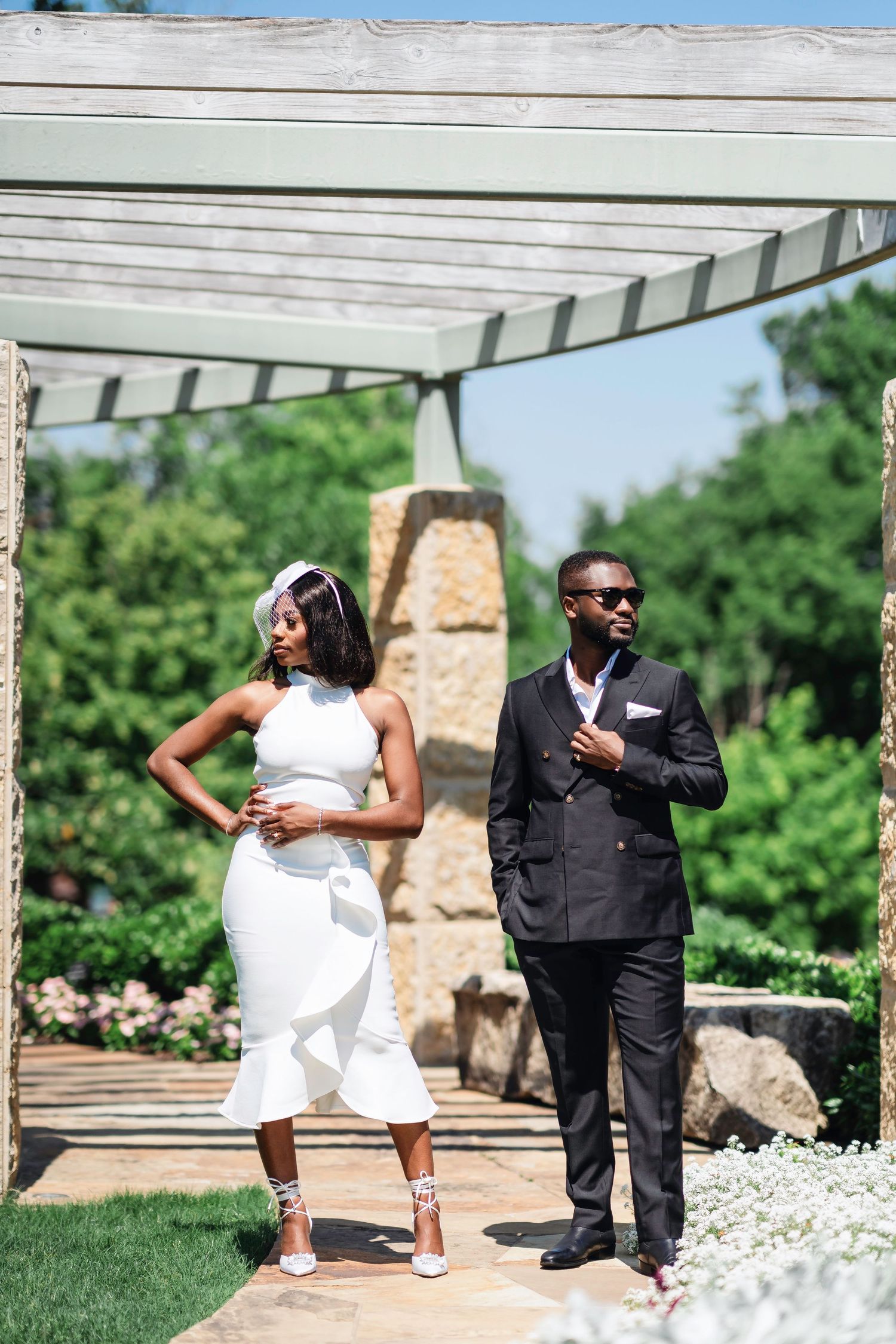 A couple dances and poses together on an outdoor patio with white flowers in the foreground.