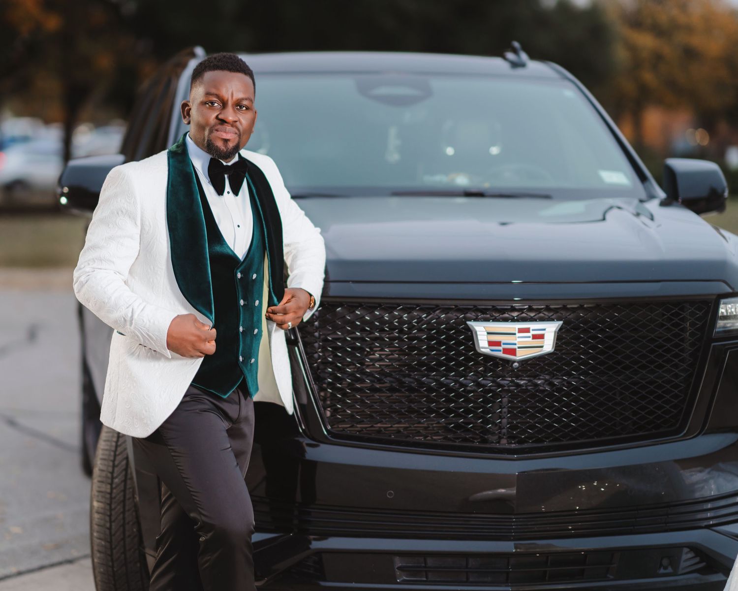 A black Cadillac luxury car is shown in detail with its distinctive grille and emblem.