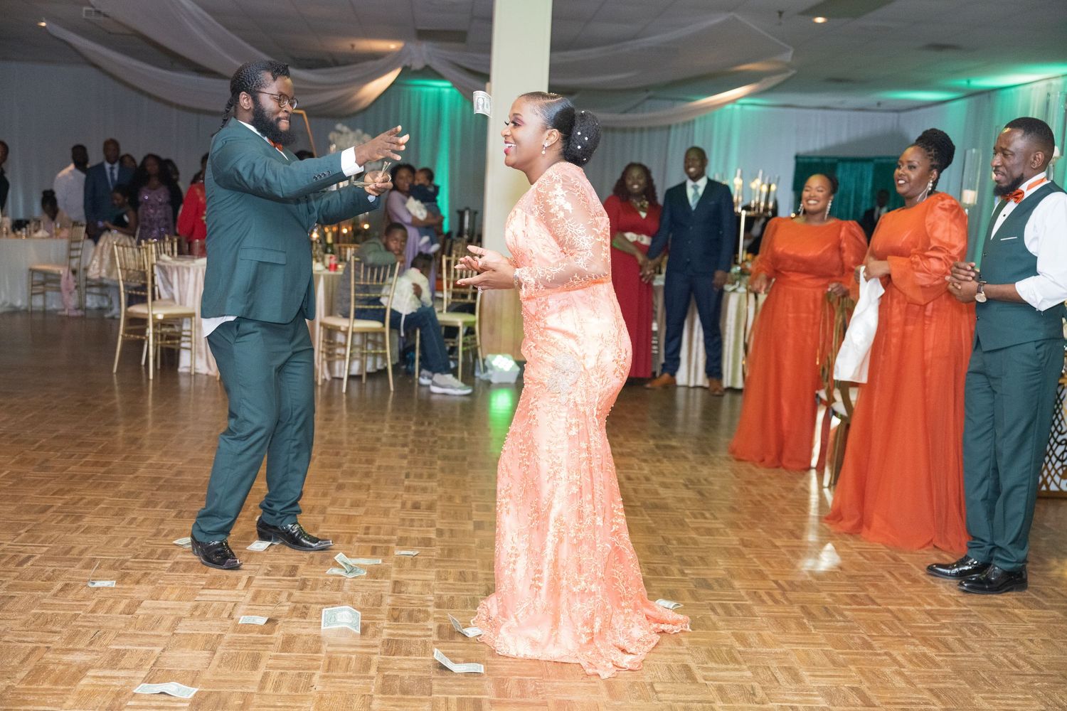 Wedding reception dance party with guests in formal attire and orange bridesmaid dresses.