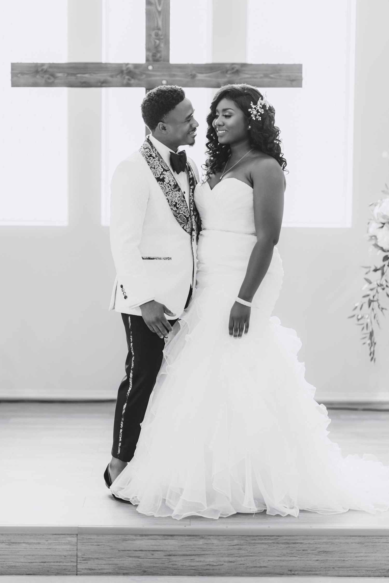 Romantic wedding couple sitting together in an elegant white venue with natural lighting.
