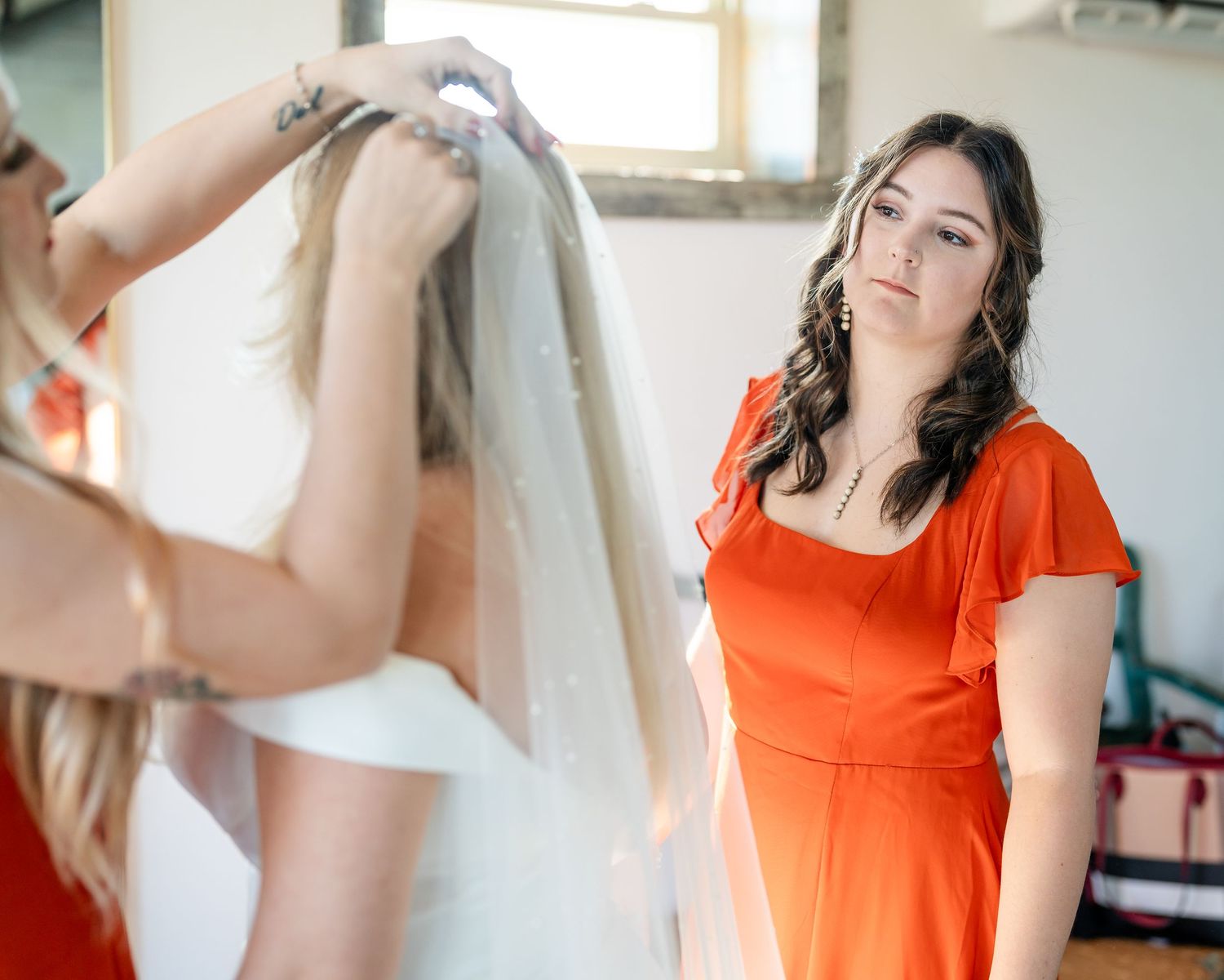 Bridesmaid in coral dress helping with wedding preparations.
