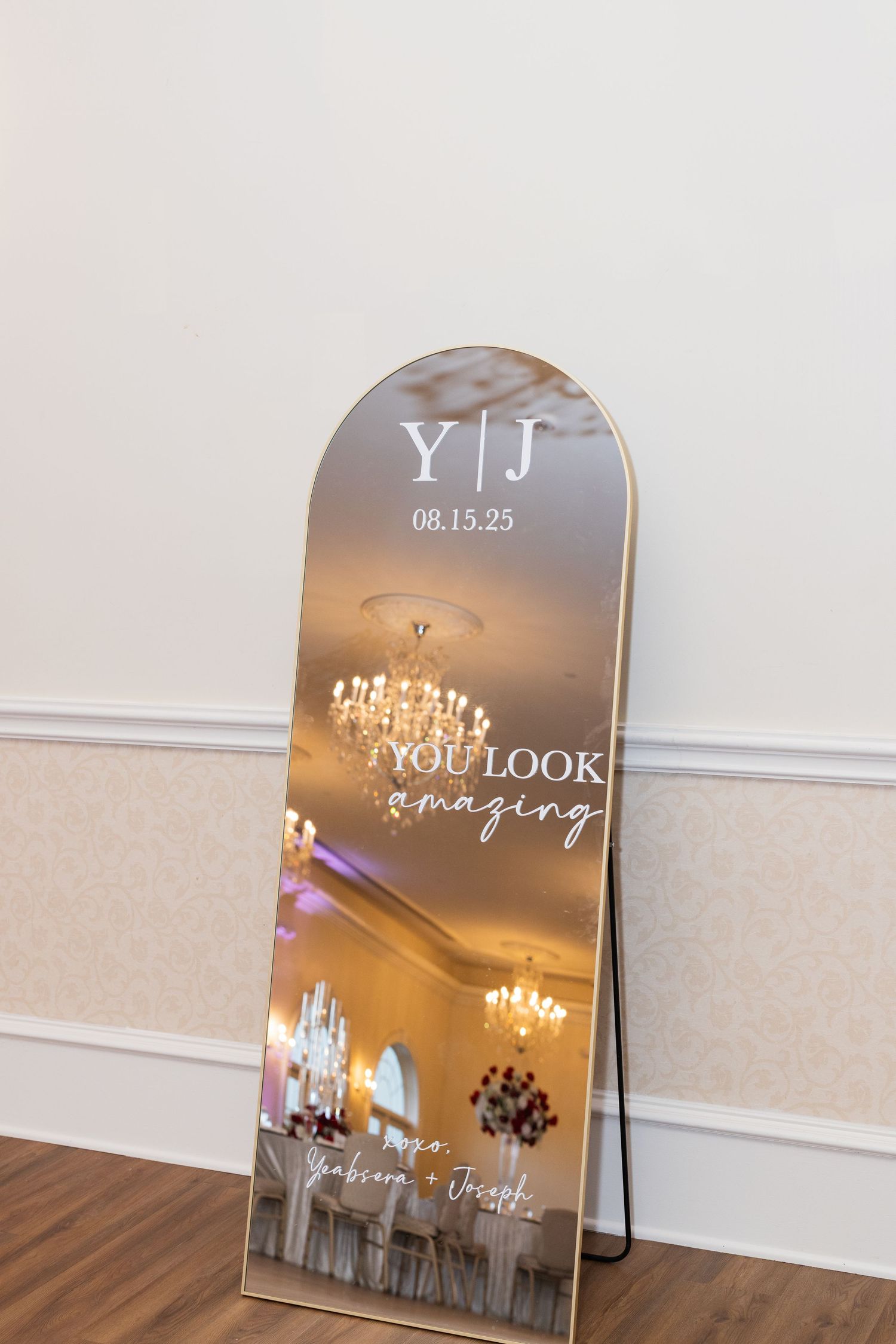Decorative wedding mirror signs with elegant text and chandelier reflections.