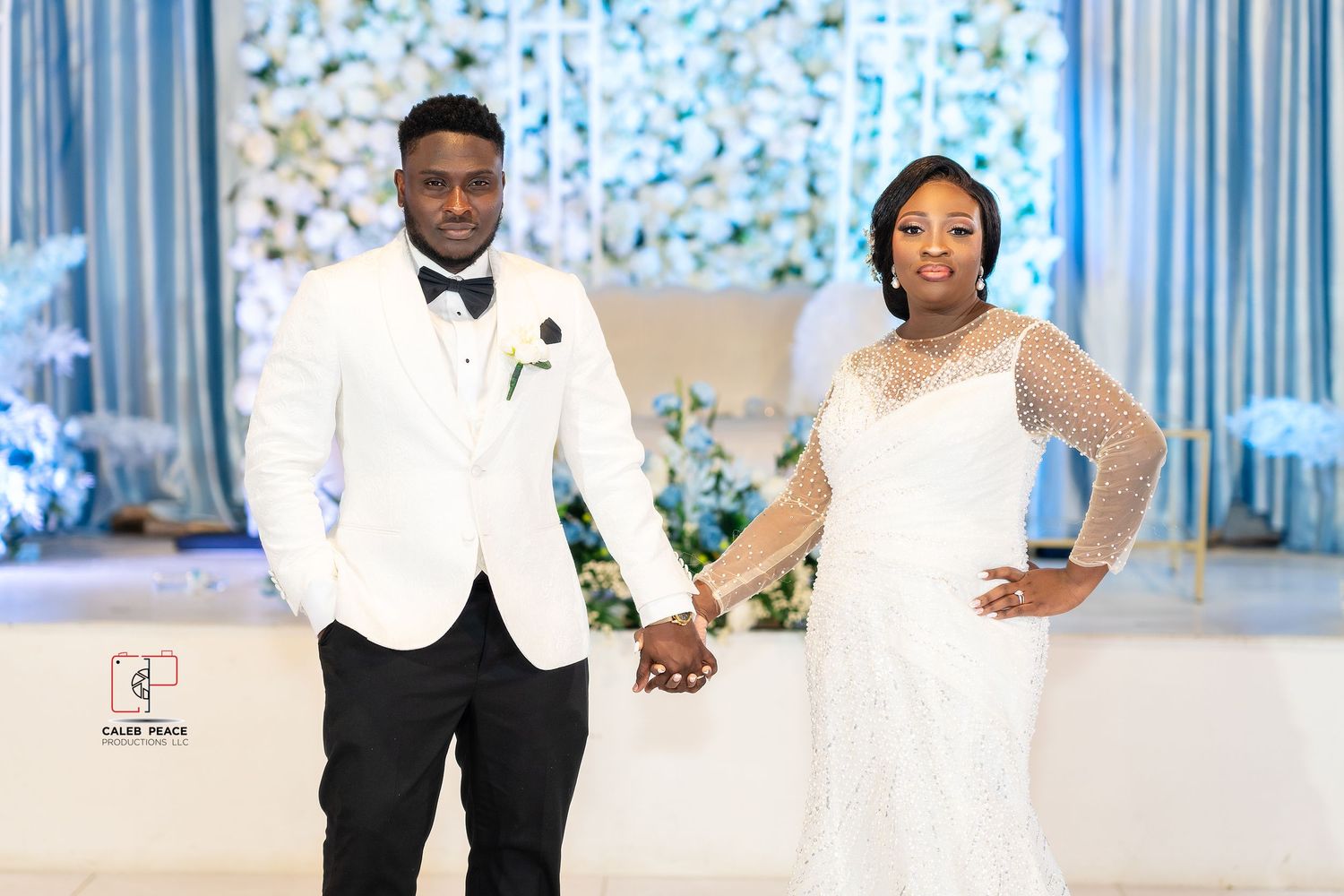Wedding reception scene with formal attire and decorative blue lighting and backdrops.