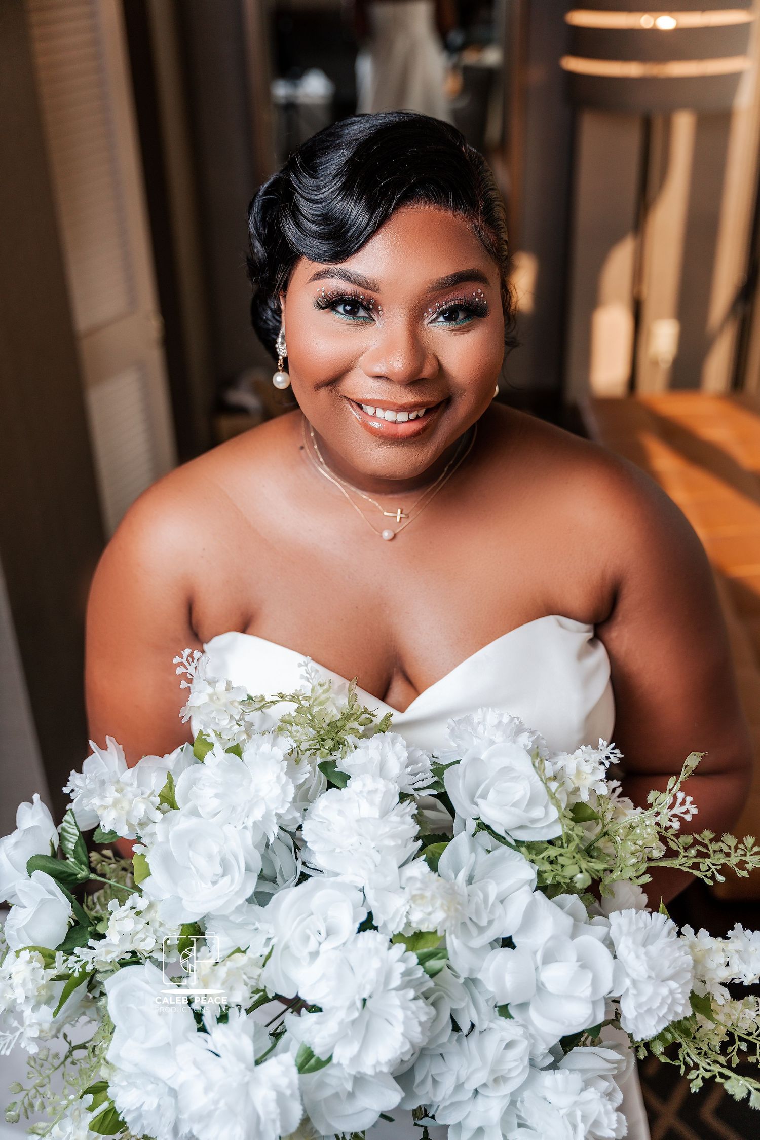 Beautiful bride in strapless white wedding dress holding elegant bouquet of white roses and delicate florals.