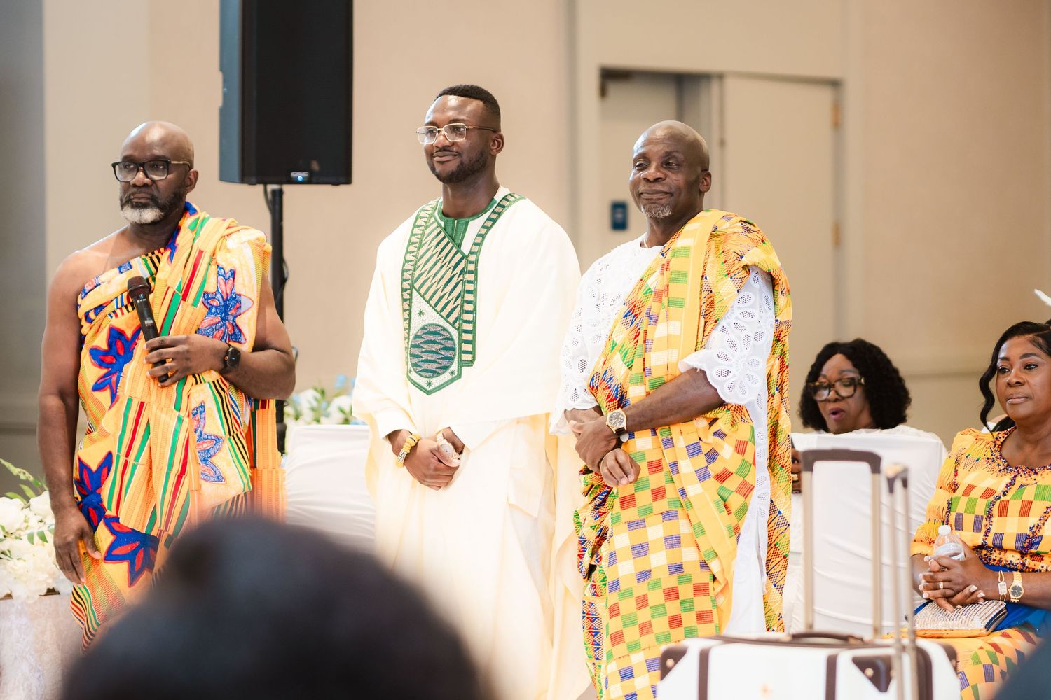 Wedding guests in colorful African prints gathered at celebratory event.