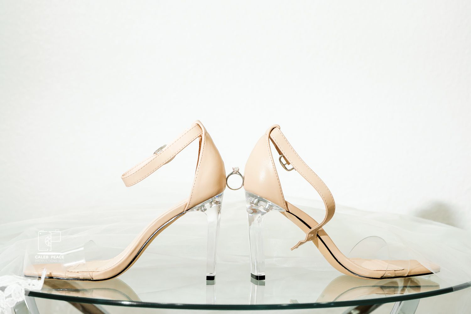 Elegant bridal shoes in soft nude tones arranged on white background.