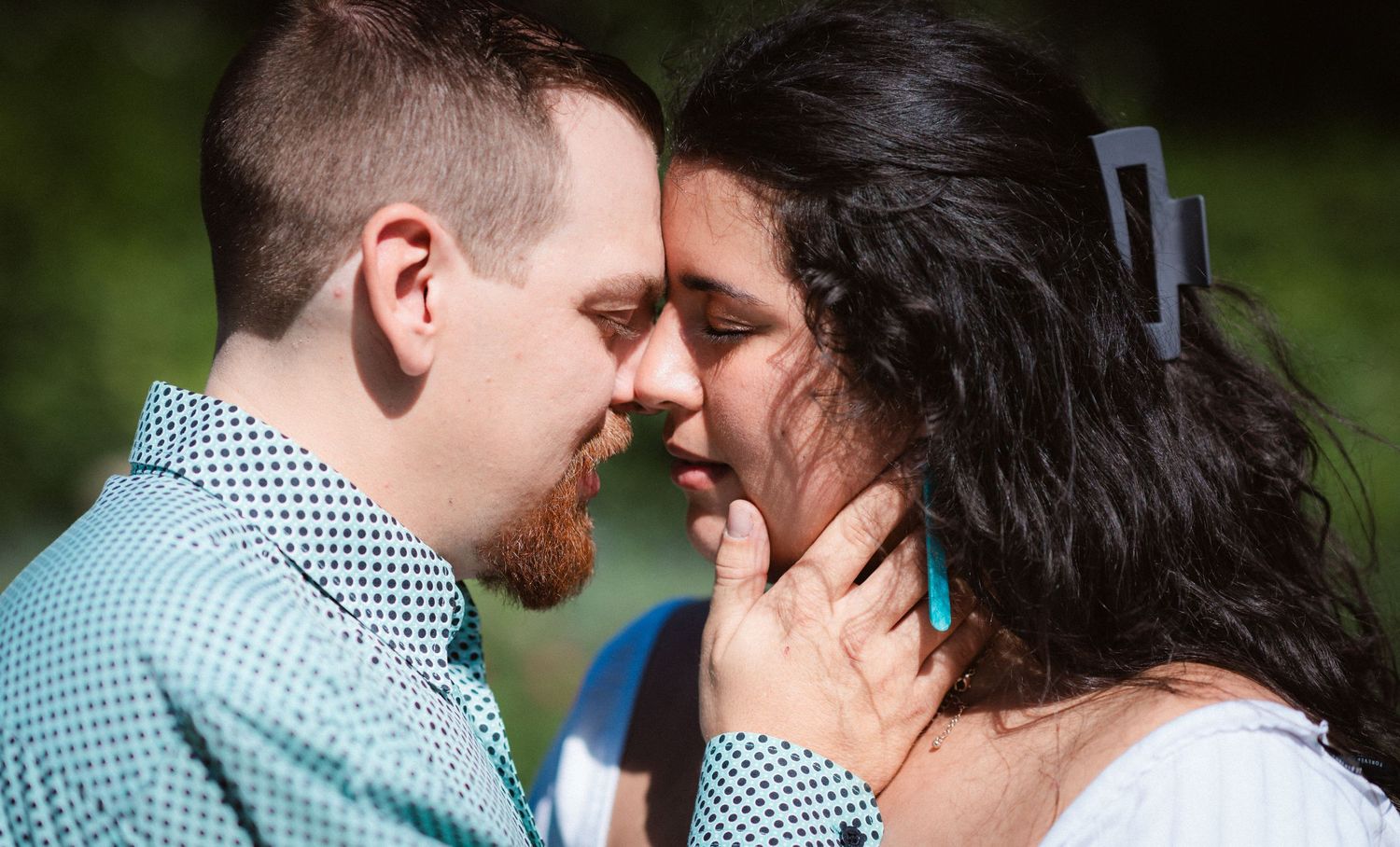 A tender romantic moment captured between a couple in close embrace outdoors.