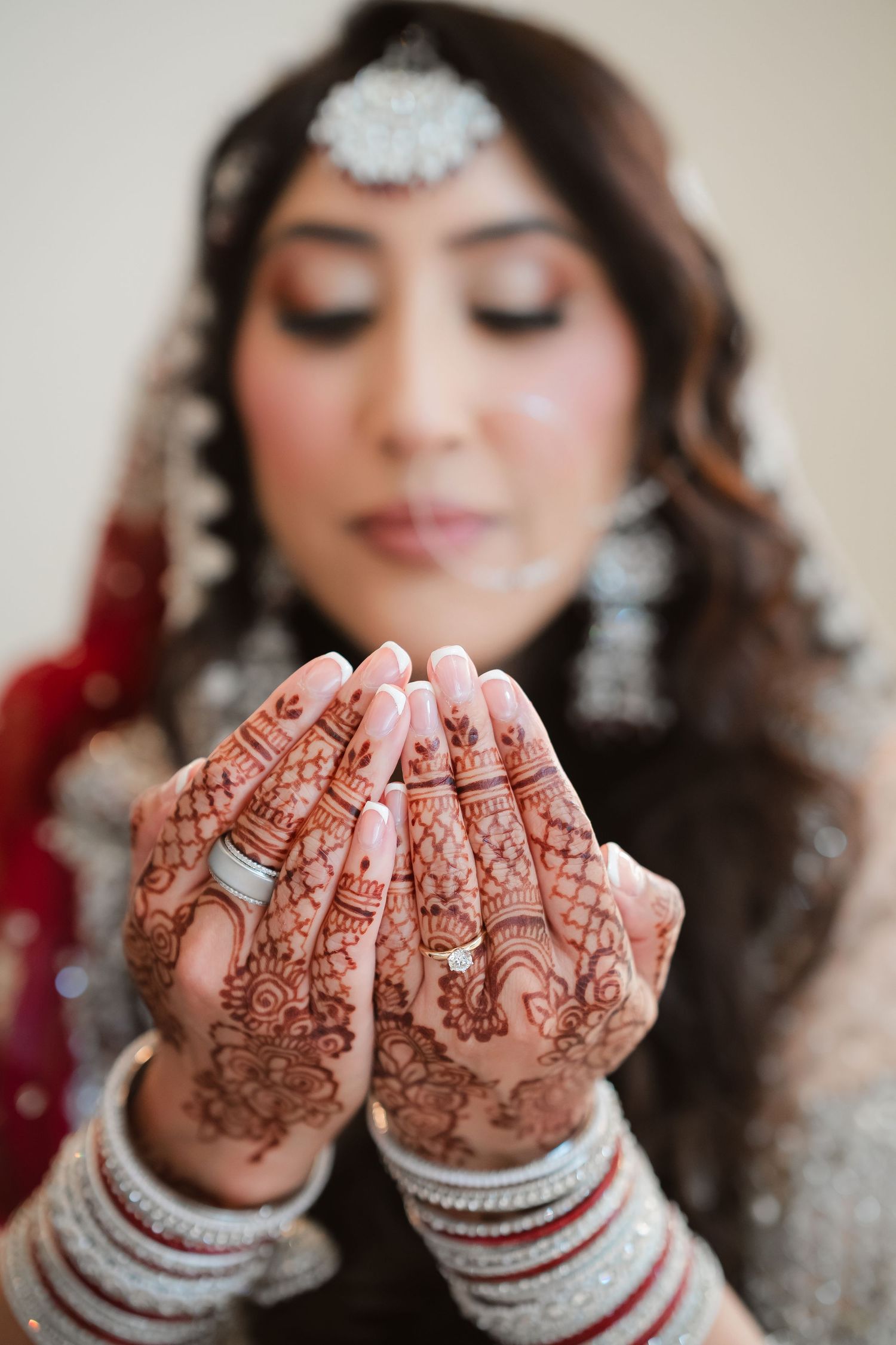 Detailed henna designs adorn hands held up in a prayer position.