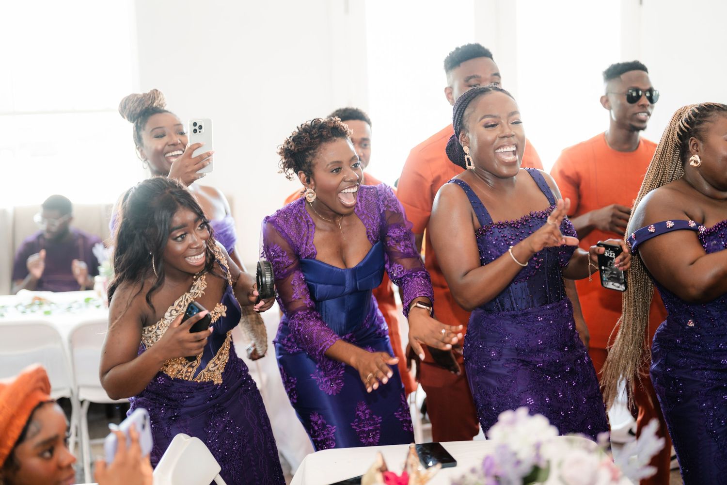 Wedding guests in purple dresses laughing and celebrating together at a reception.
