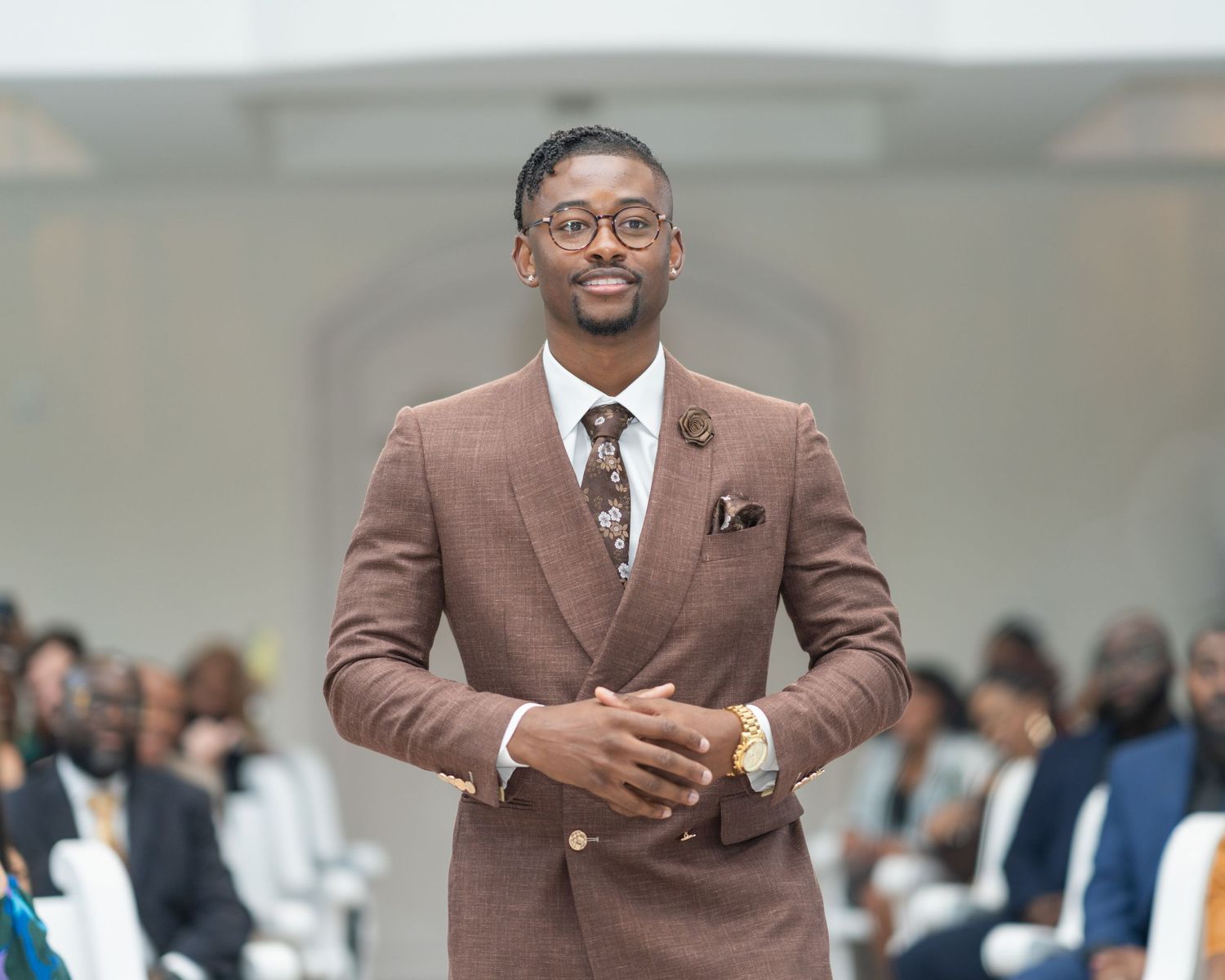 A collage of four photos showing someone in a brown double-breasted suit speaking at a formal event.