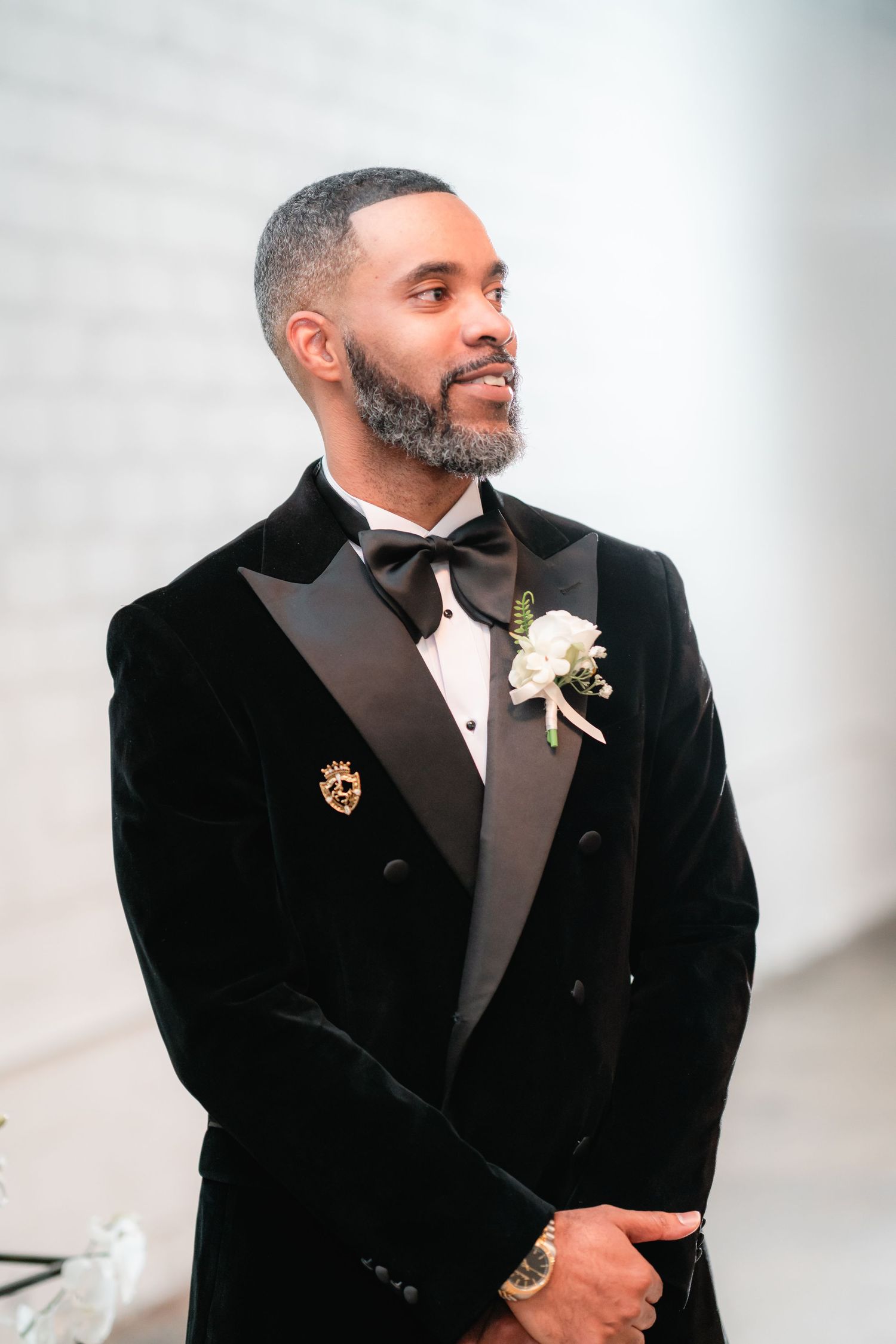 Groom wearing velvet tuxedo with boutonniere smiles during formal portraits.