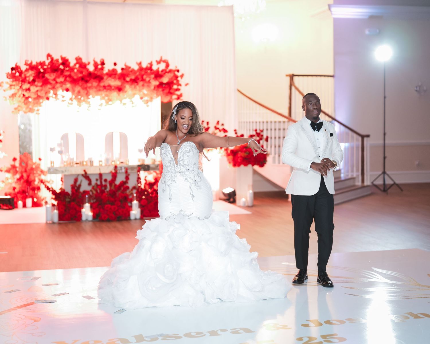 Wedding reception venue decorated with dramatic red lighting and white decor elements.