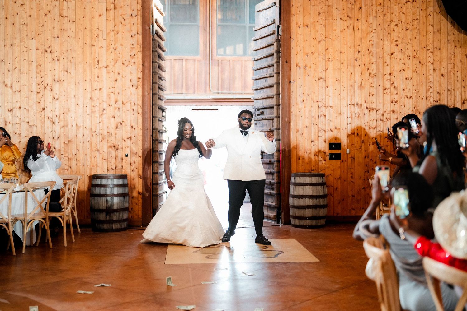 Wedding guests dancing and celebrating in a rustic barn venue with string lights.