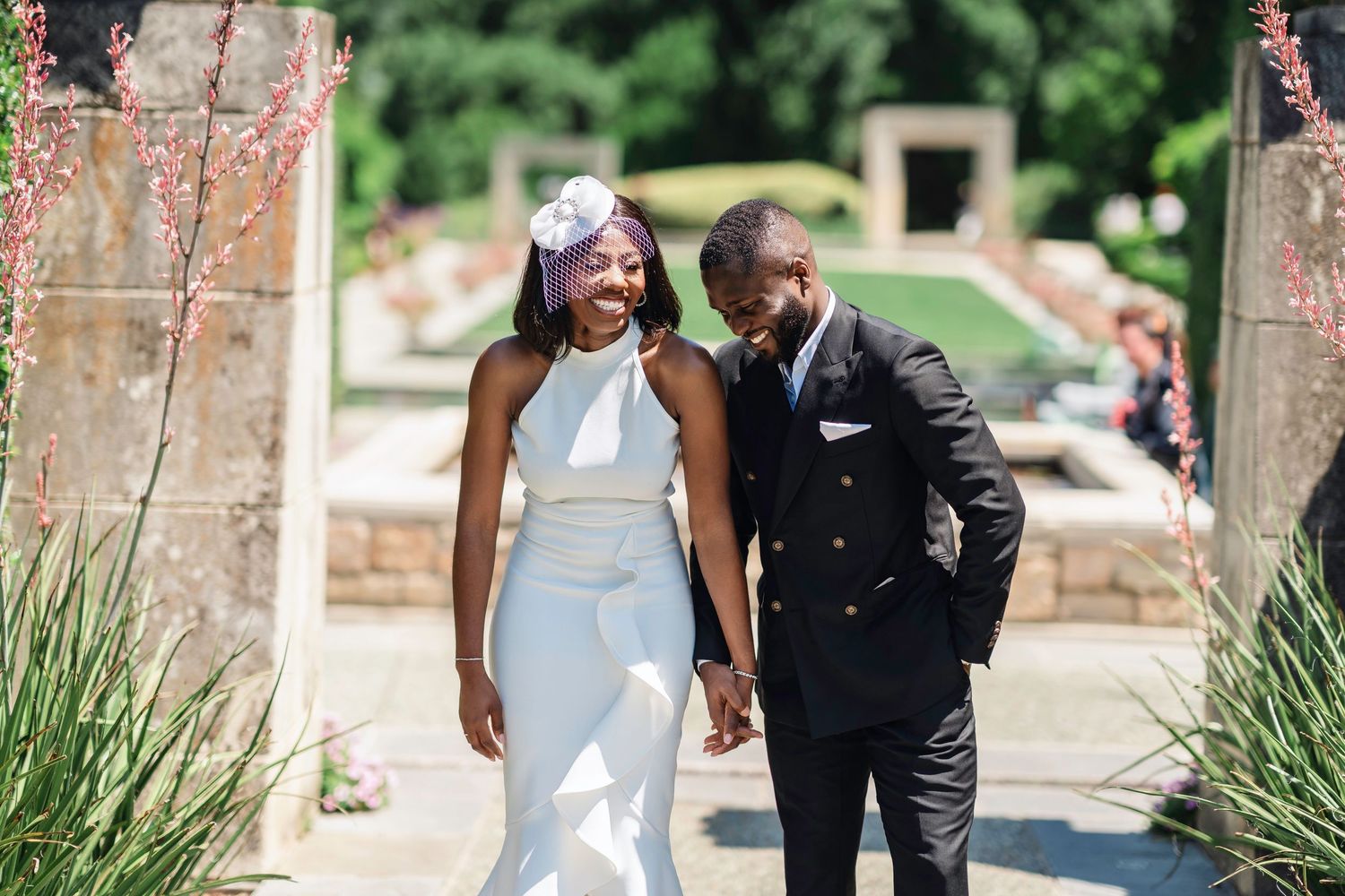 A couple shares a tender moment while walking through a garden pathway.