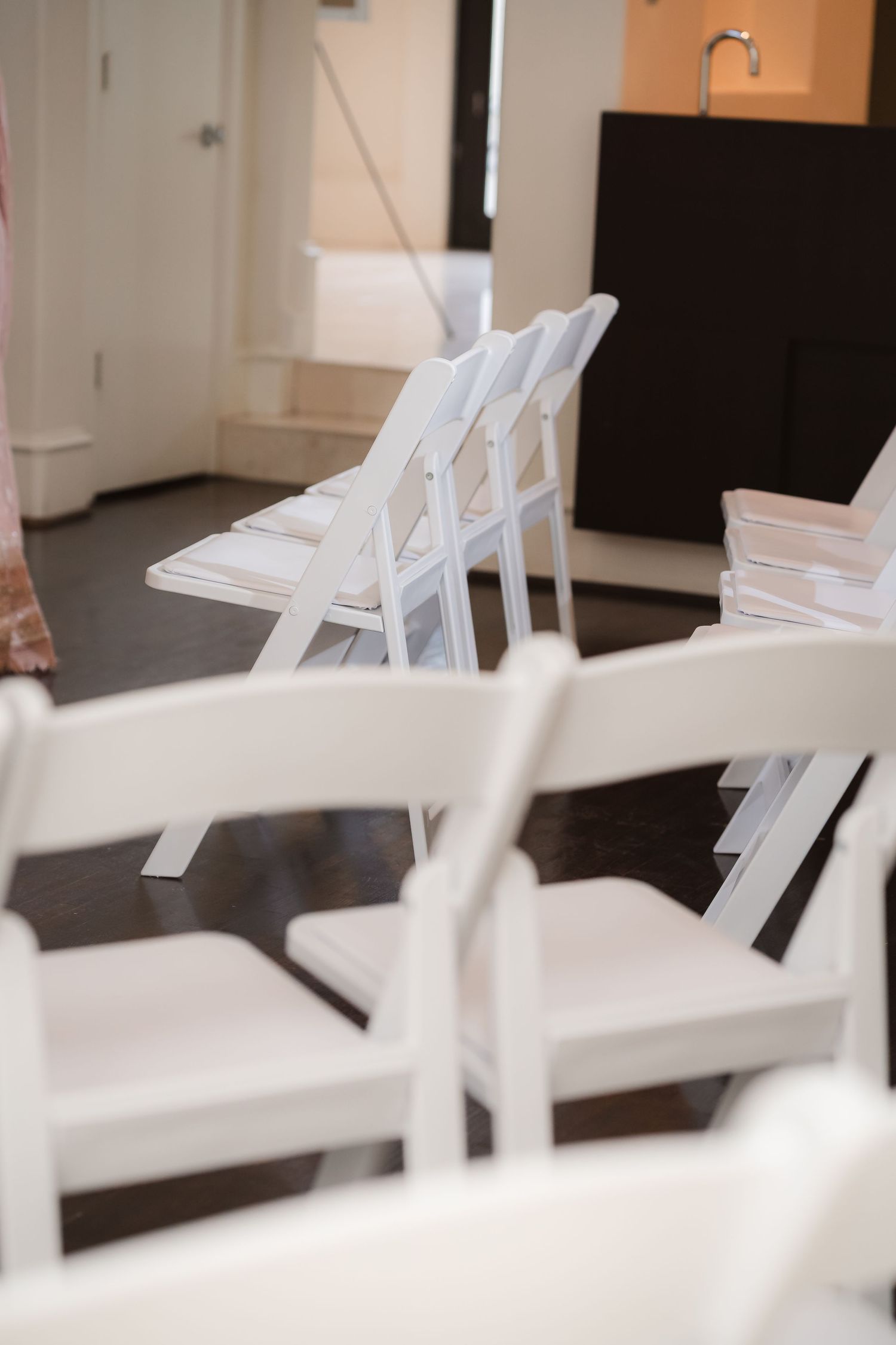 Row of white folding chairs arranged for wedding ceremony.