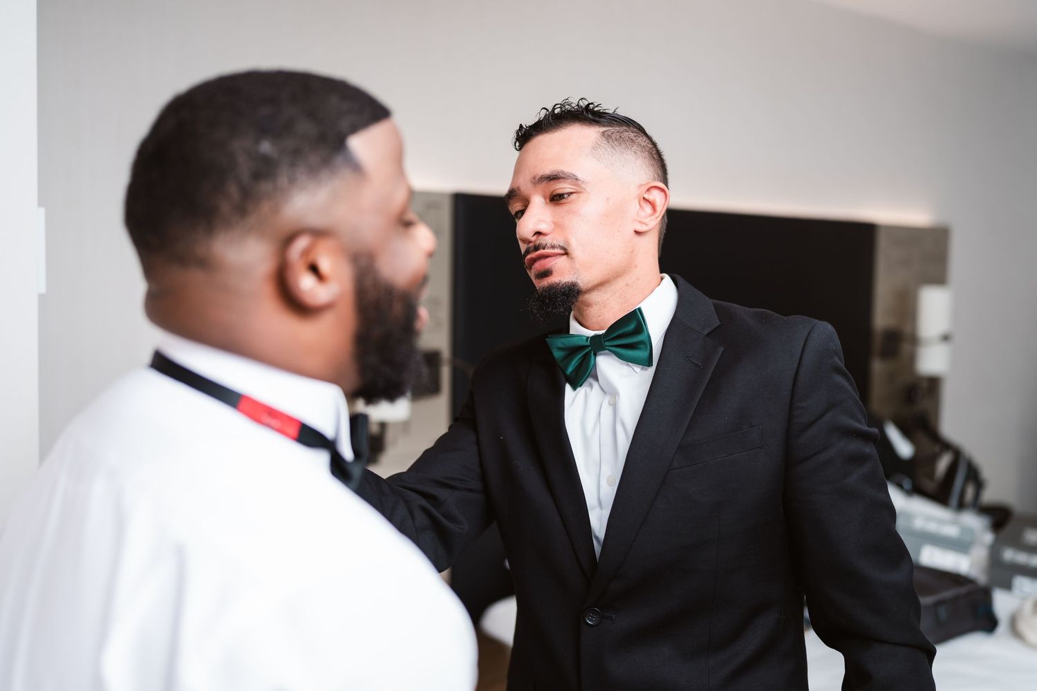 Groomsmen sharing candid moments while getting ready in formal attire.