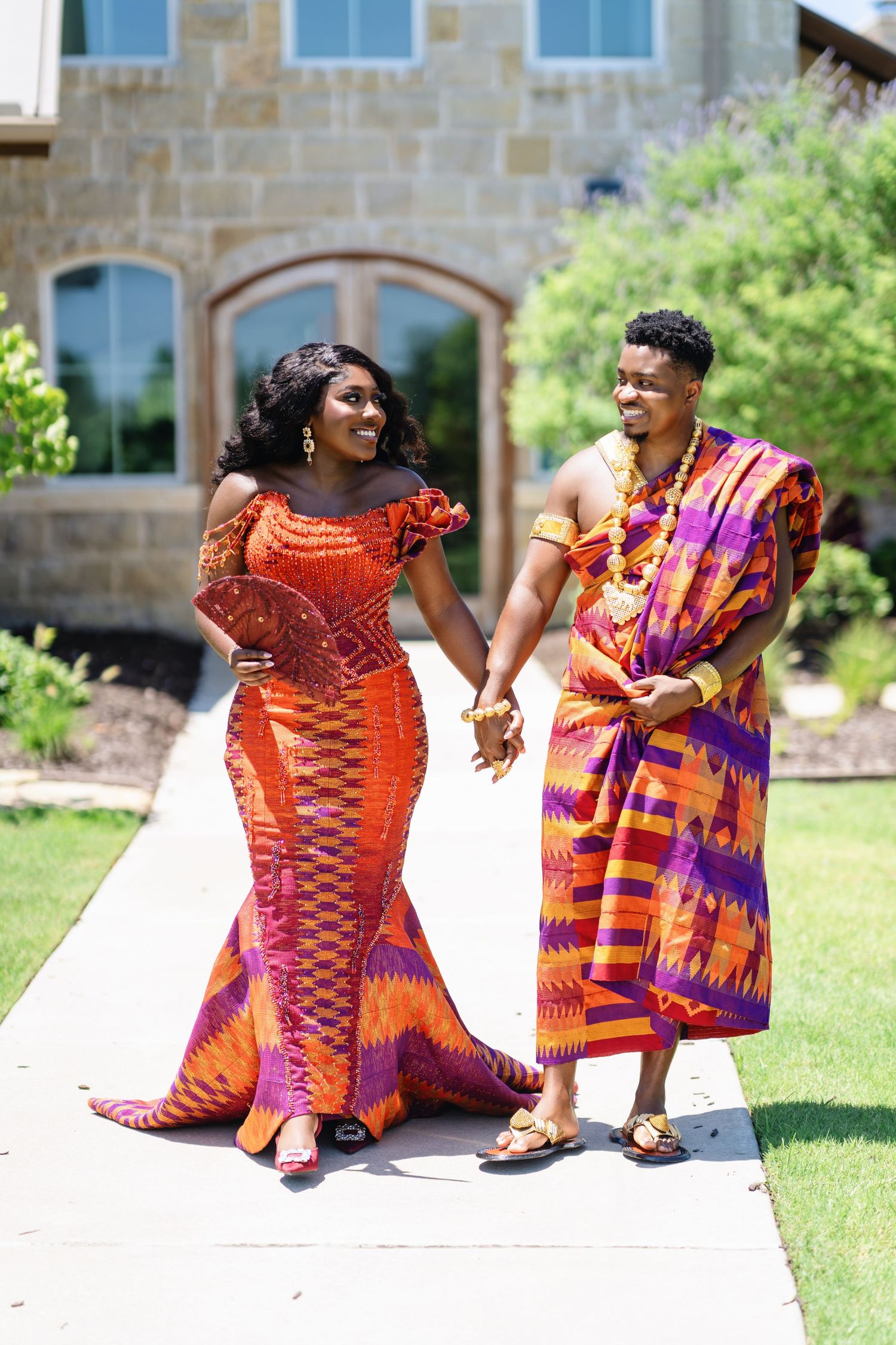 Outdoor photo session featuring traditional African wedding attire against stone building.